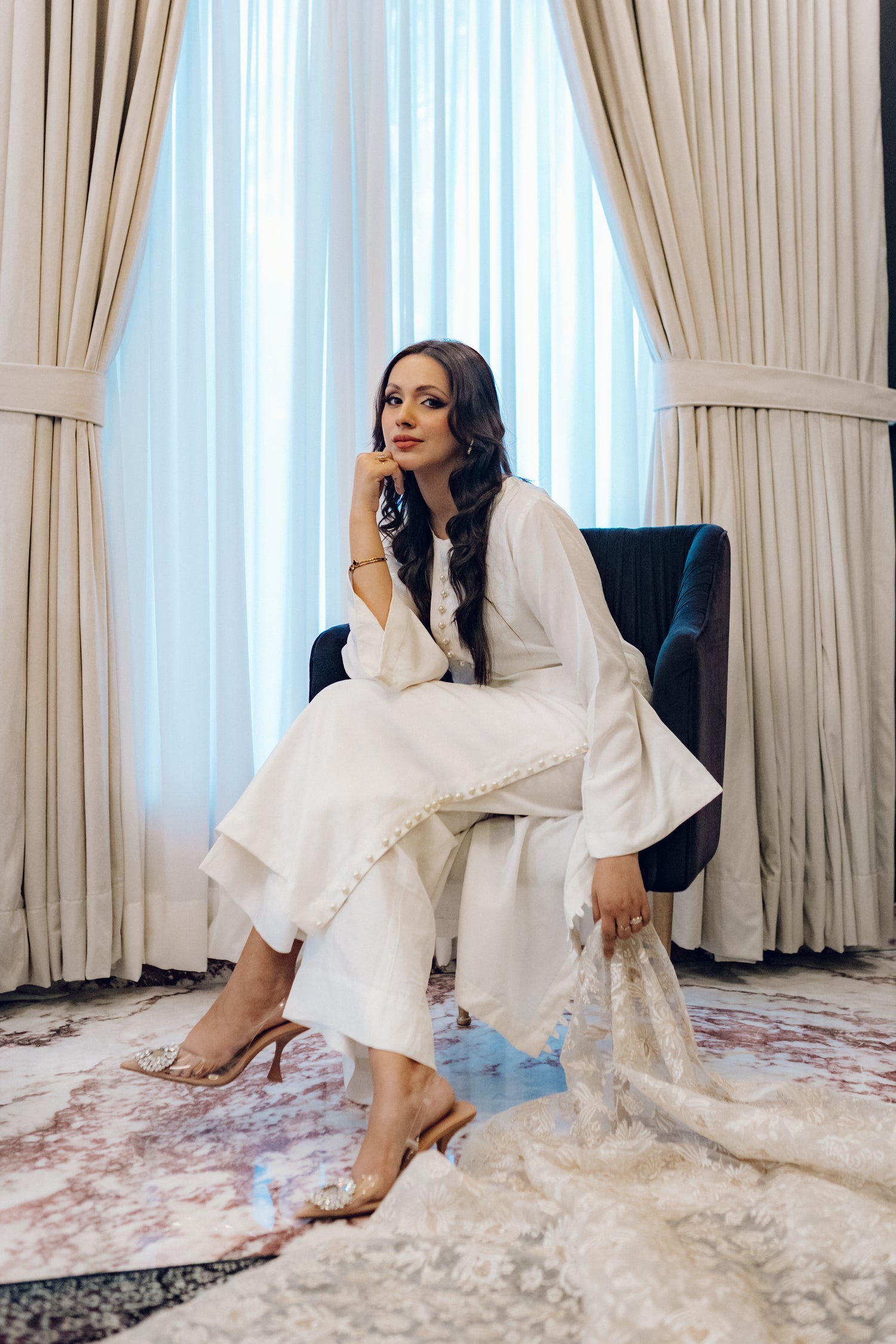 Ivory dress featuring delicate pearl buttons, paired with a shimmering tila and intricate threadwork dupatta, showcasing timeless elegance and artisanal craftsmanship.