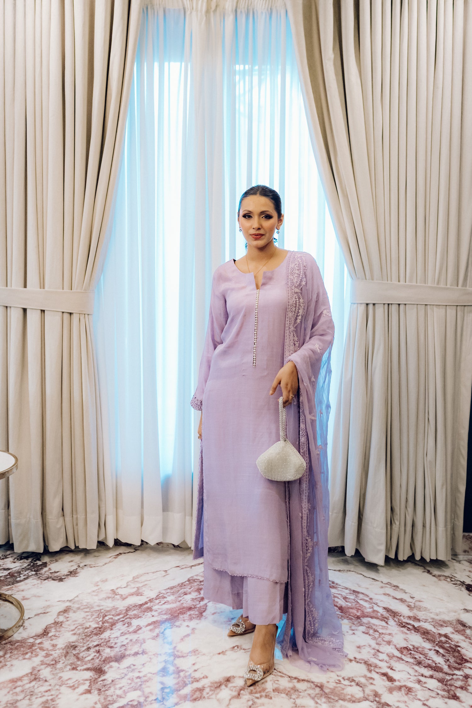 Lilac long shirt with pearl-buttoned neckline, lace-detailed hem, and embroidered sleeves, paired with a chiffon dupatta featuring matching floral embroidery for ethereal look.