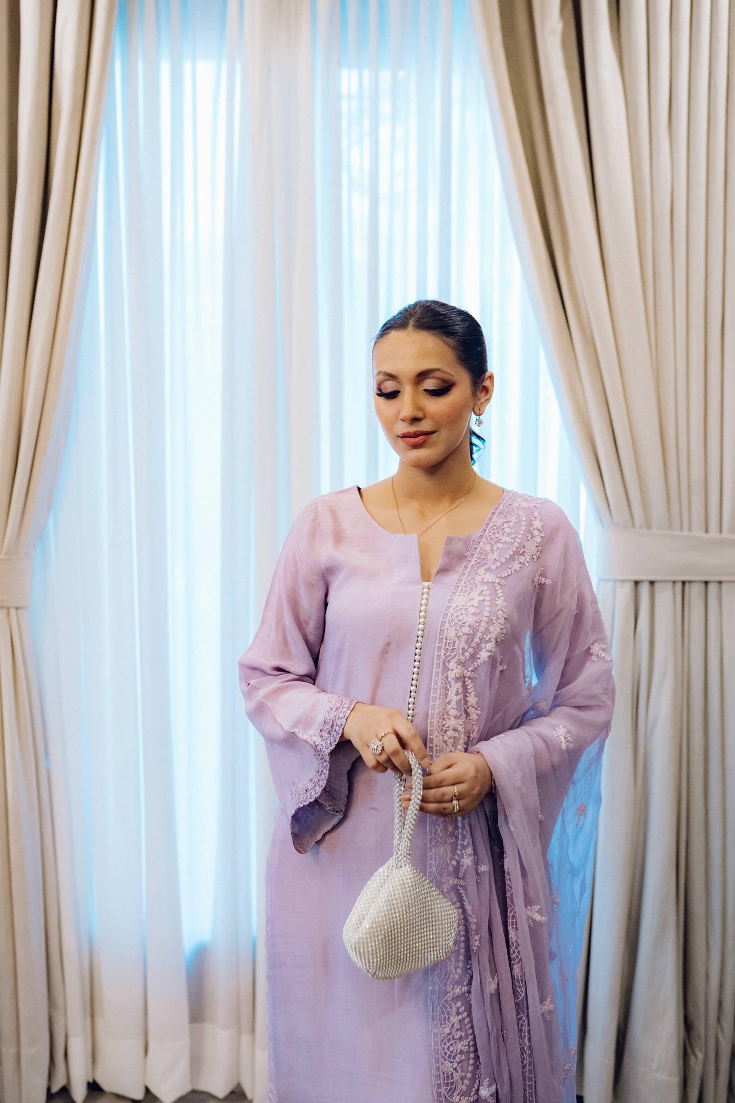 Lilac long shirt with pearl-buttoned neckline, lace-detailed hem, and embroidered sleeves, paired with a chiffon dupatta featuring matching floral embroidery for ethereal look.
