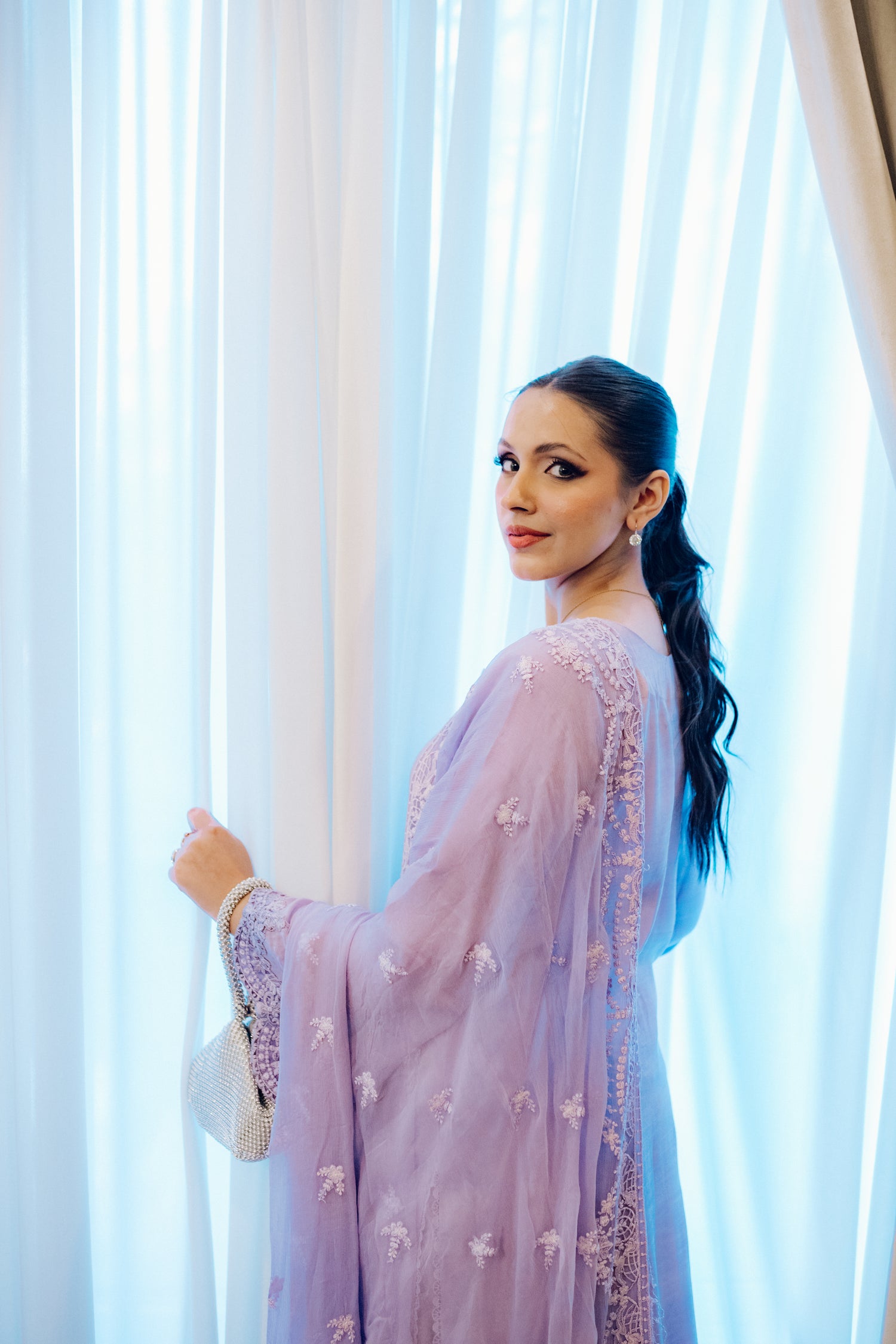 Lilac long shirt with pearl-buttoned neckline, lace-detailed hem, and embroidered sleeves, paired with a chiffon dupatta featuring matching floral embroidery for ethereal look.