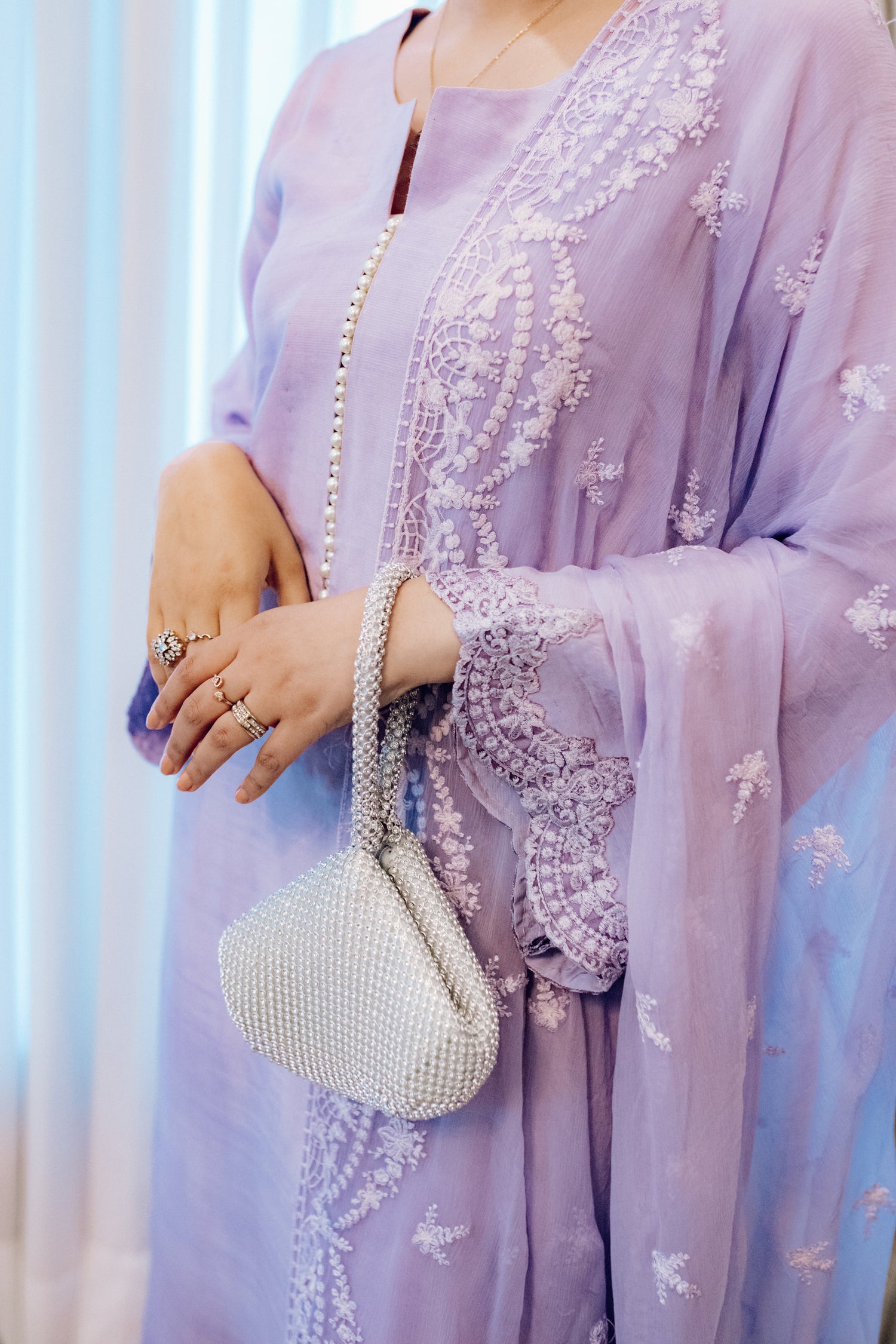 Lilac long shirt with pearl-buttoned neckline, lace-detailed hem, and embroidered sleeves, paired with a chiffon dupatta featuring matching floral embroidery for ethereal look.