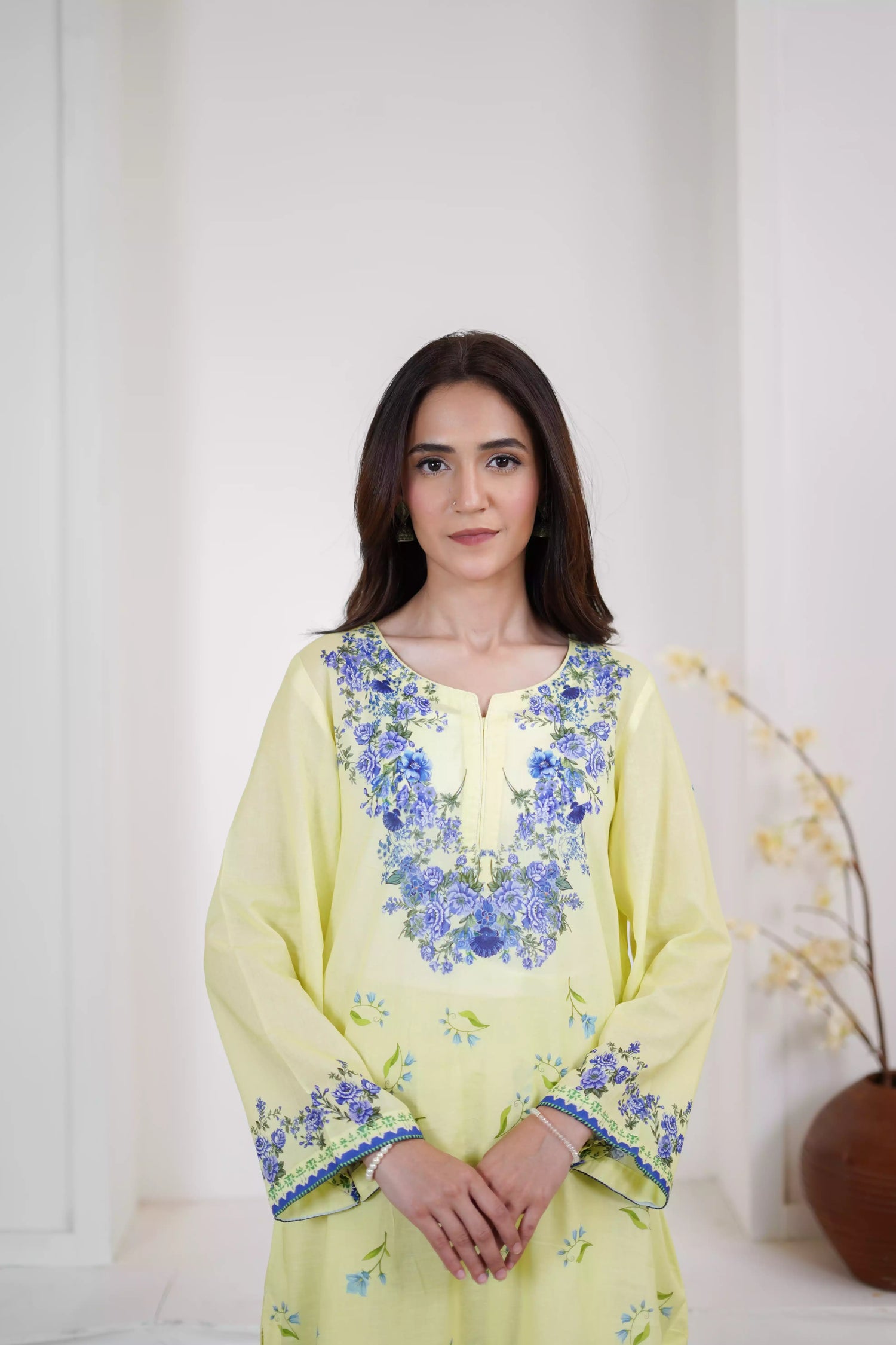A pastel yellow suit adorned with delicate blue flowers and soft green leaves. The design features a border elegance and freshness.