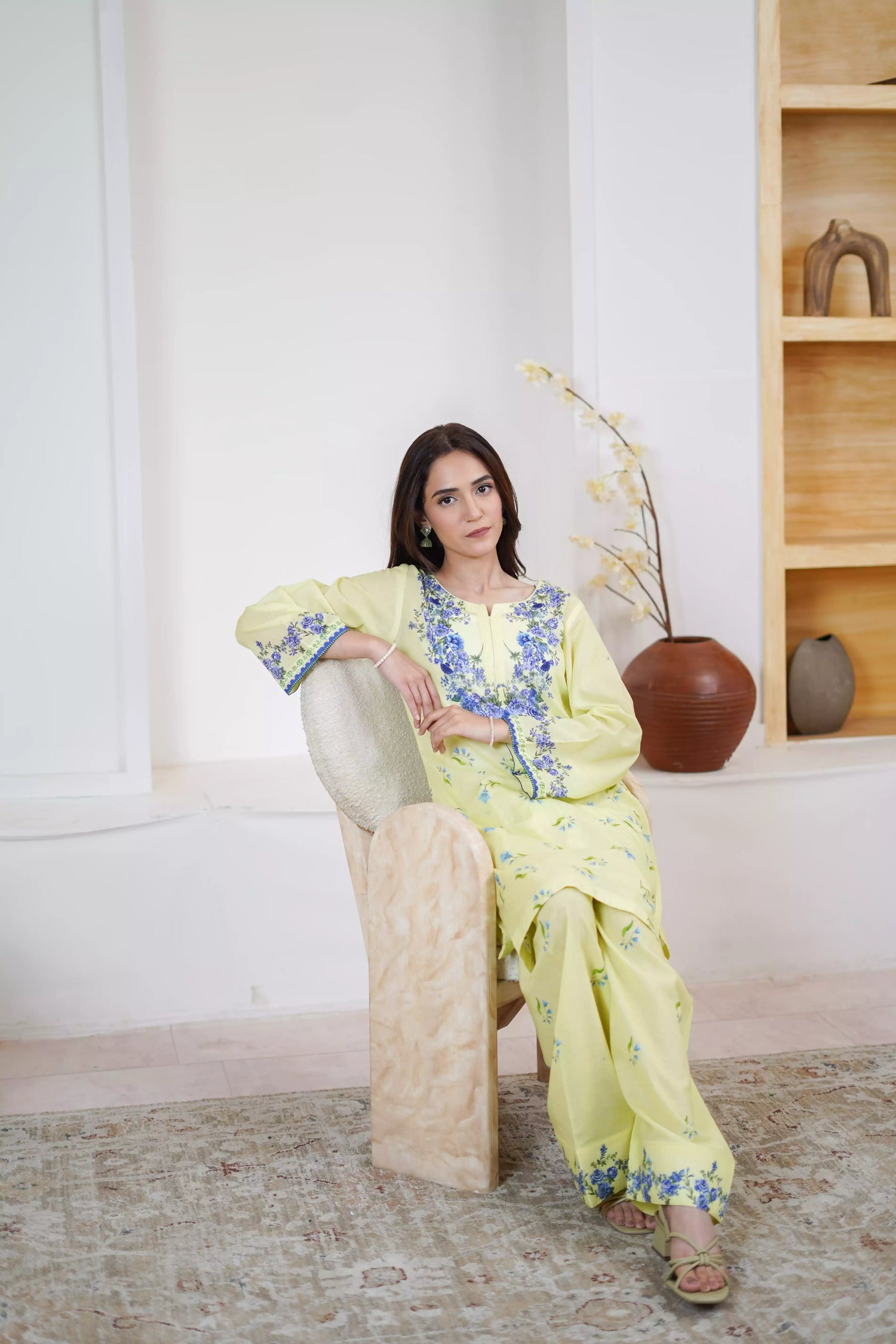 A pastel yellow suit adorned with delicate blue flowers and soft green leaves. The design features a border elegance and freshness.
