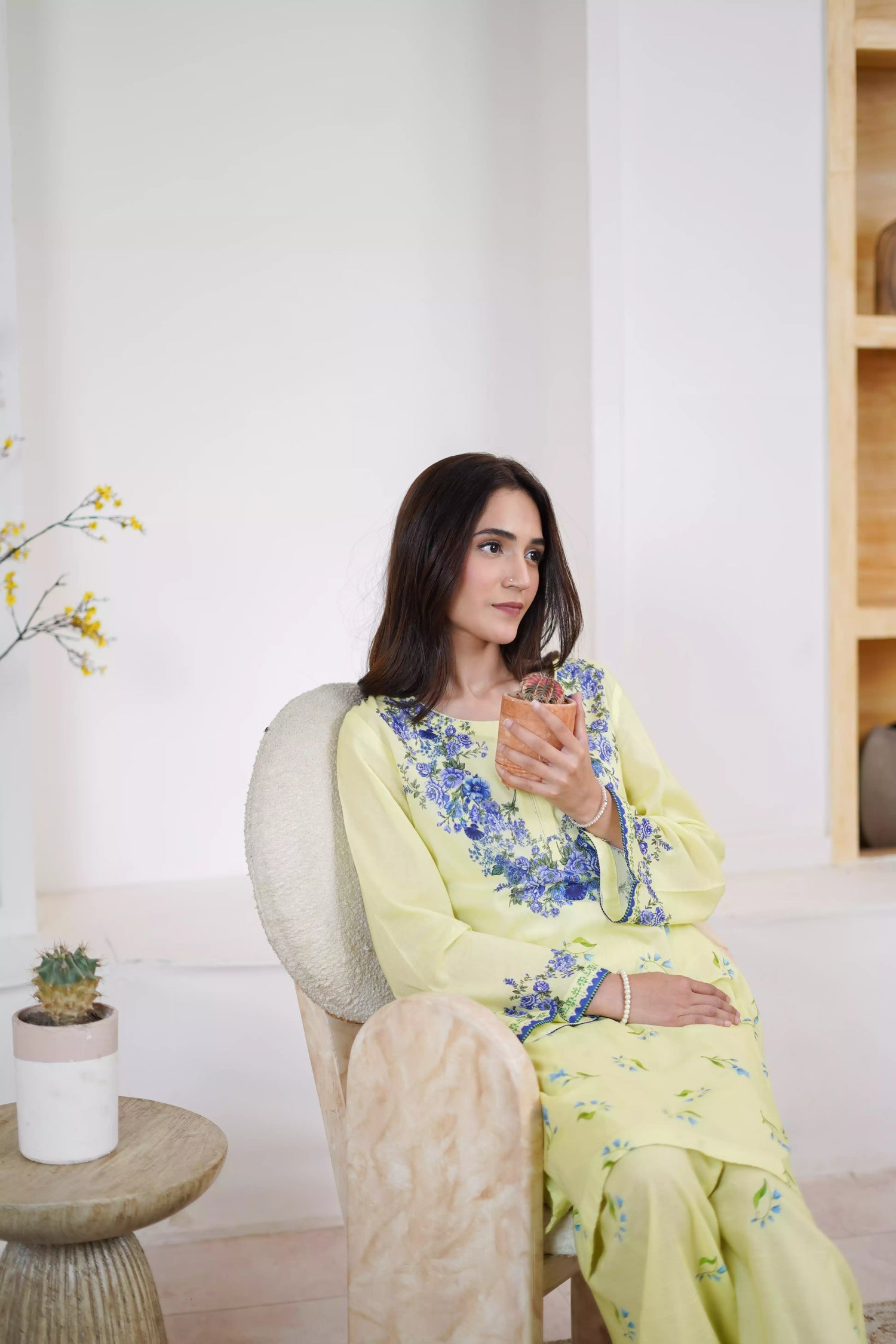 A pastel yellow suit adorned with delicate blue flowers and soft green leaves. The design features a border elegance and freshness.