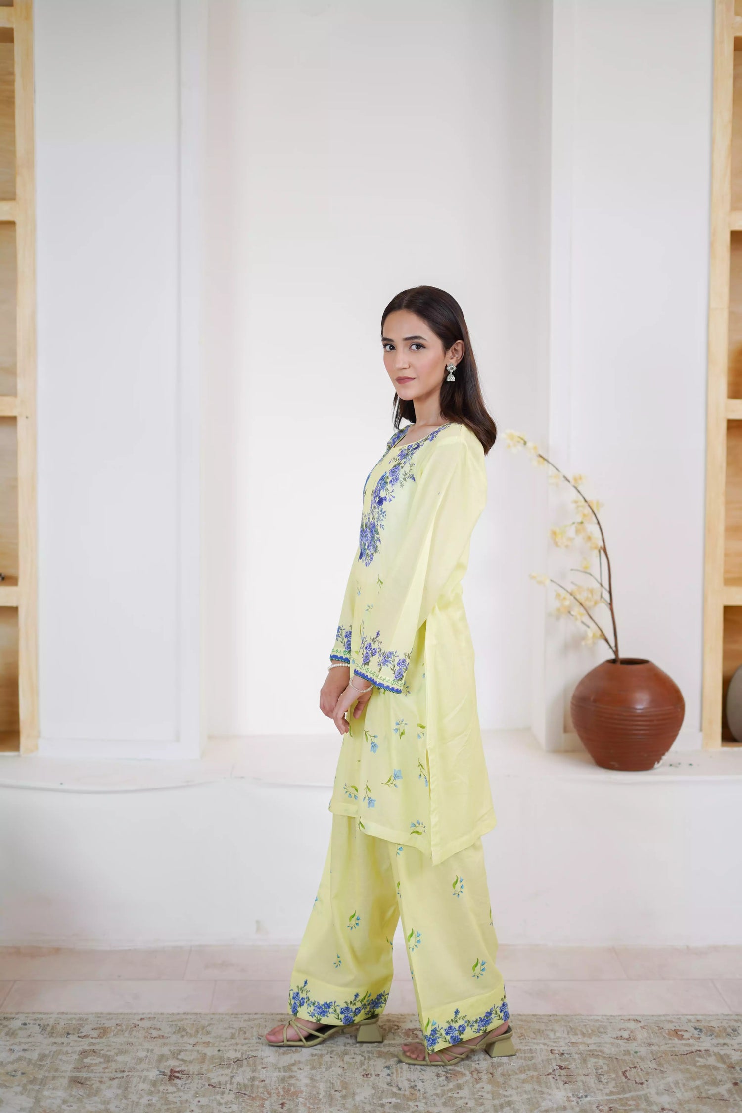 A pastel yellow suit adorned with delicate blue flowers and soft green leaves. The design features a border elegance and freshness.
