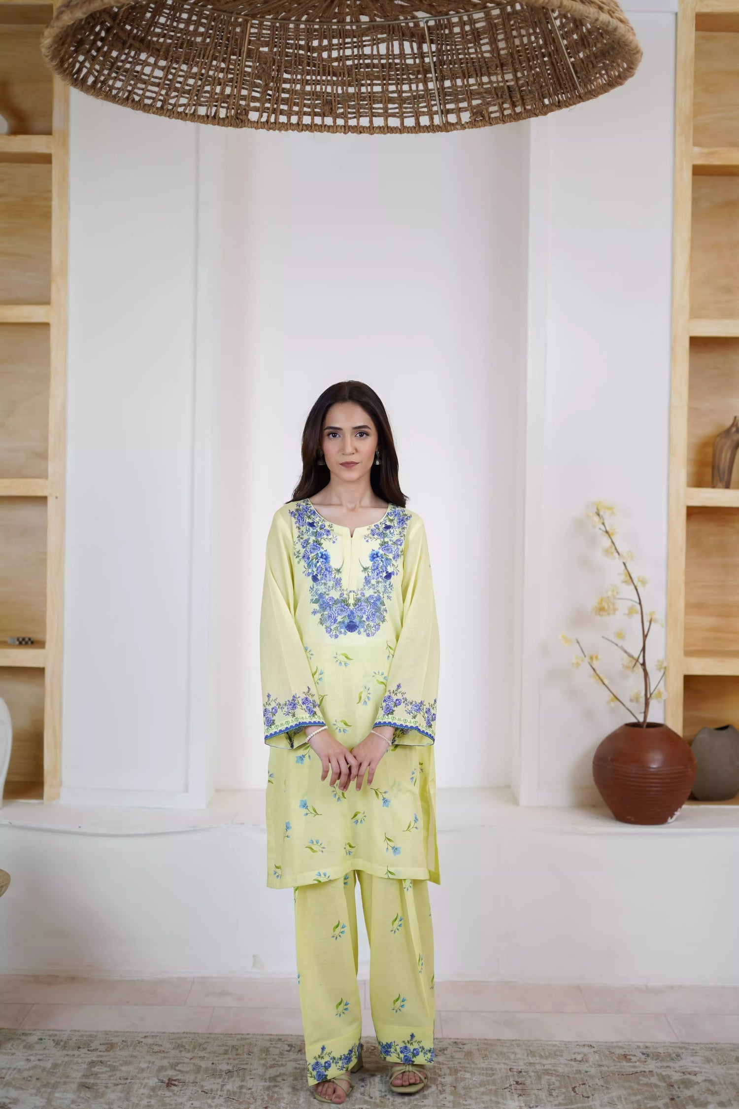 A pastel yellow suit adorned with delicate blue flowers and soft green leaves. The design features a border elegance and freshness.