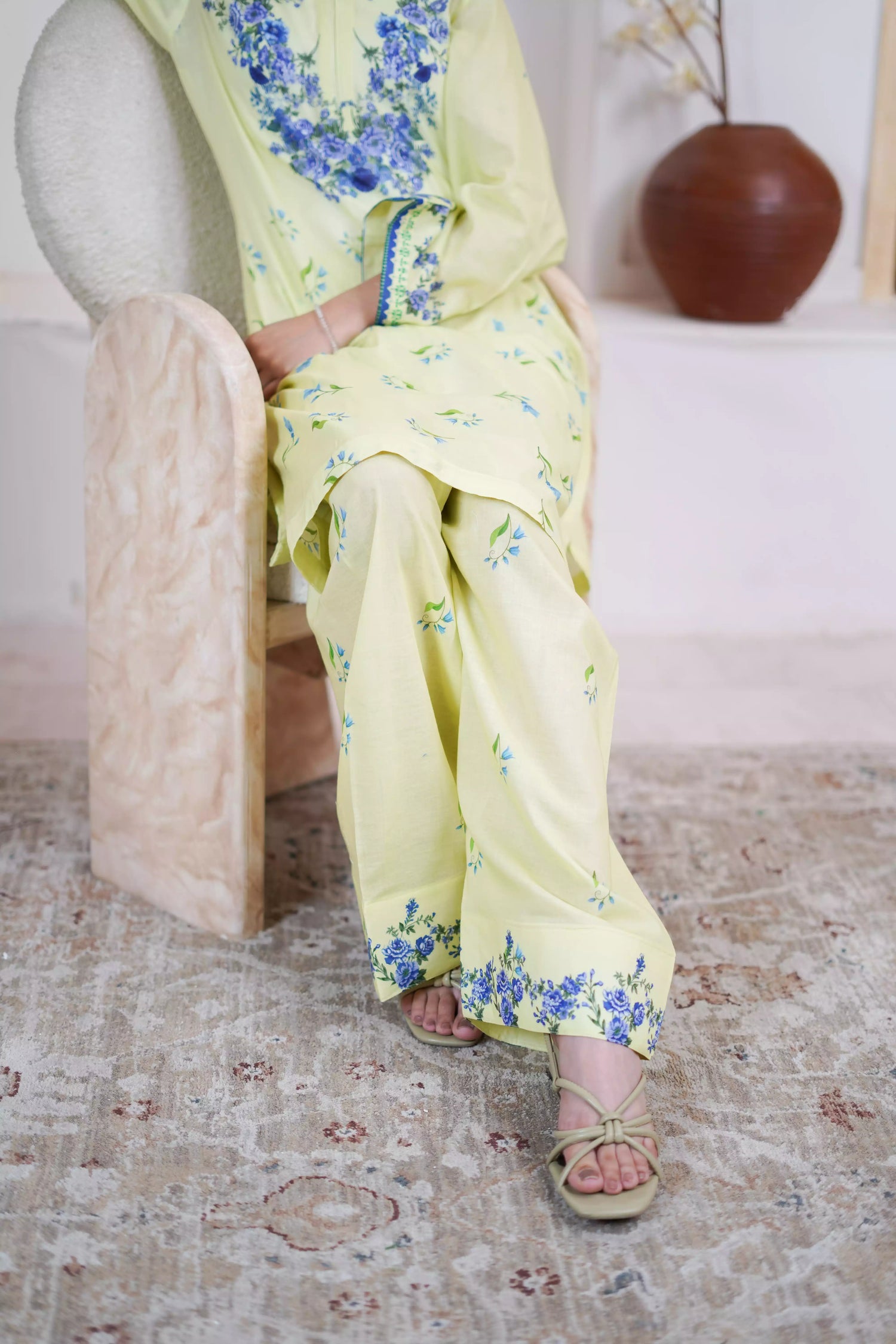 A pastel yellow suit adorned with delicate blue flowers and soft green leaves. The design features a border elegance and freshness.