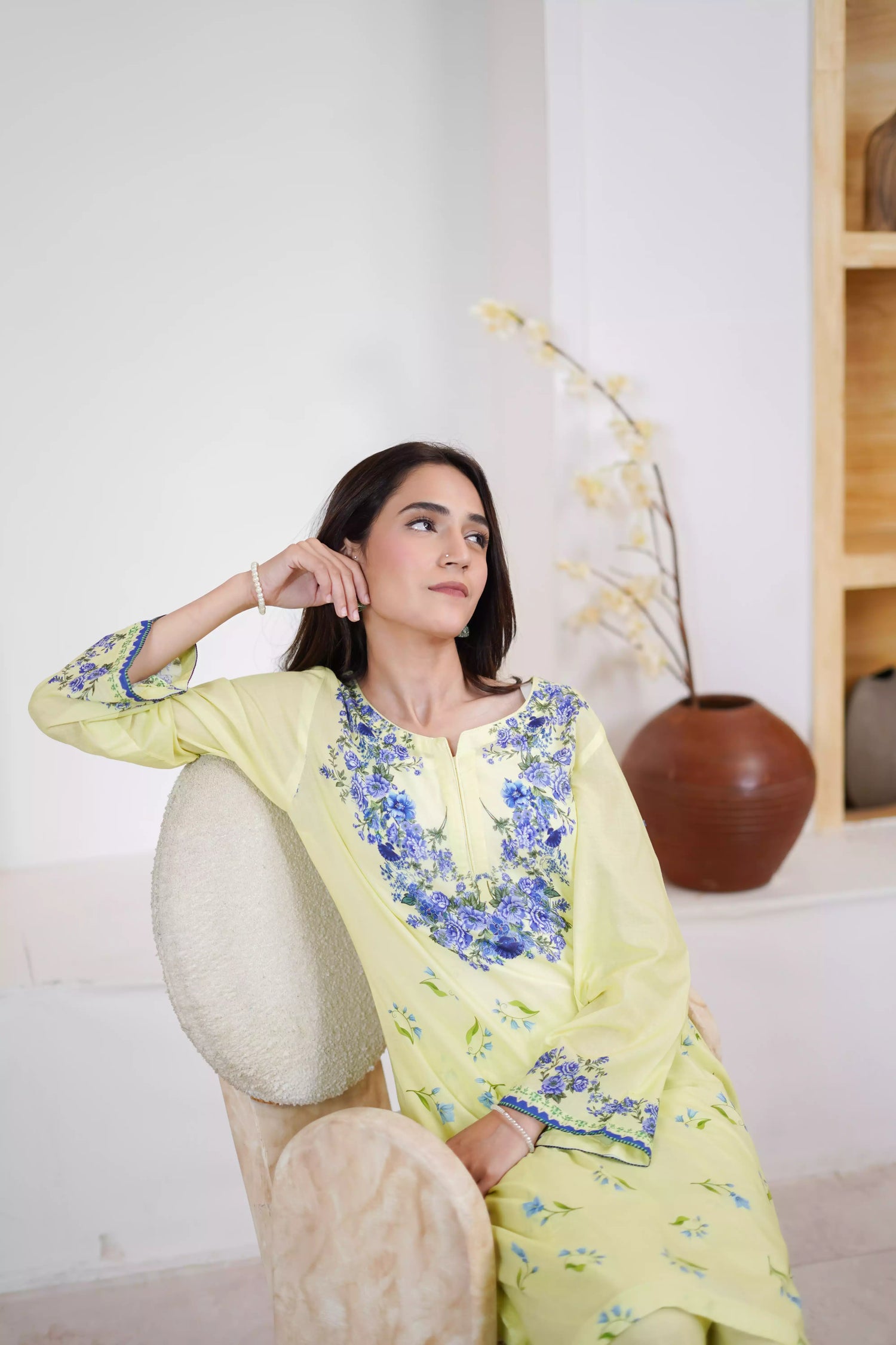 A pastel yellow suit adorned with delicate blue flowers and soft green leaves. The design features a border elegance and freshness.