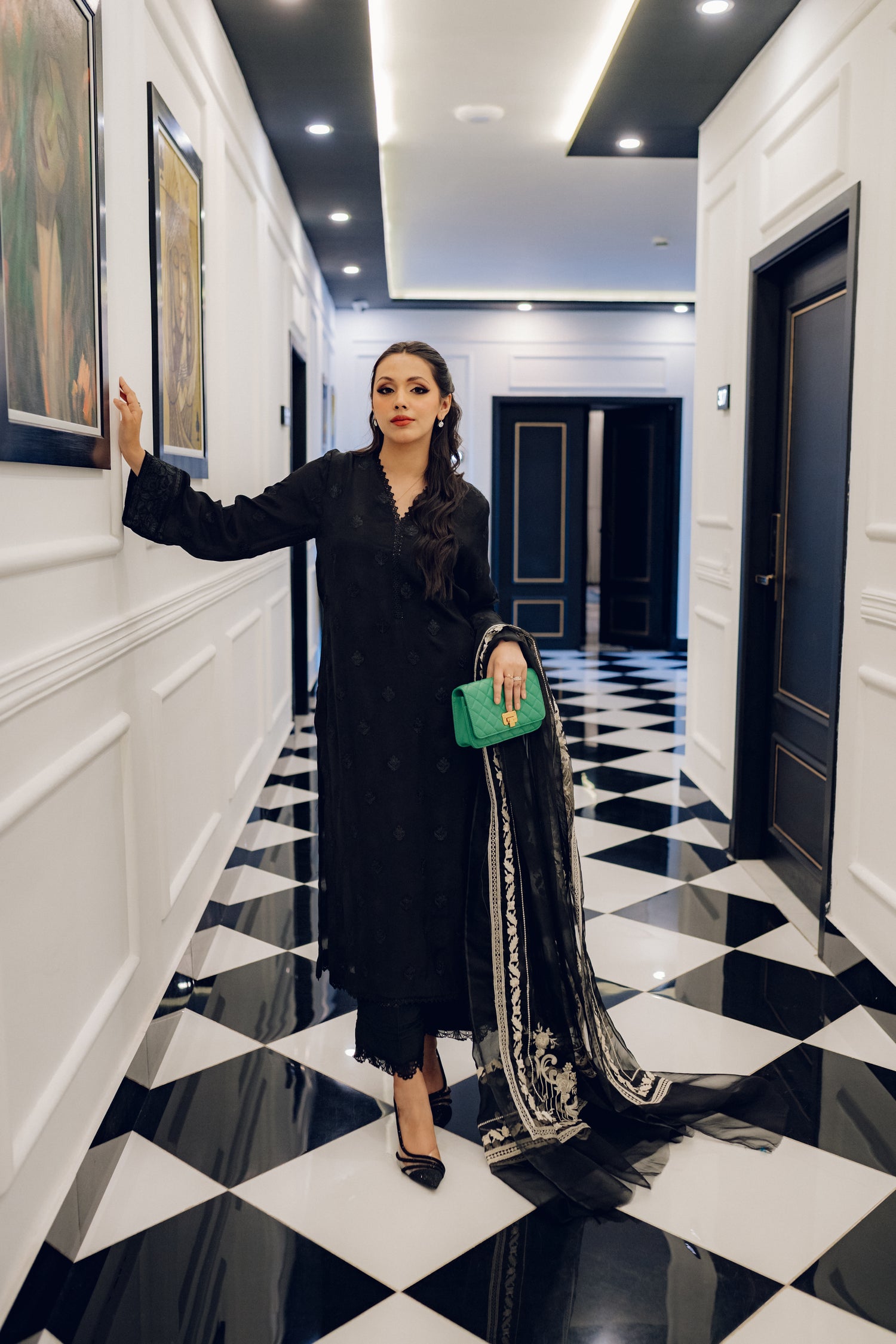 A sophisticated black embroidered dress with intricate motifs and lace detailing, paired with an organza dupatta featuring coordinated embroidery for an elegant look.