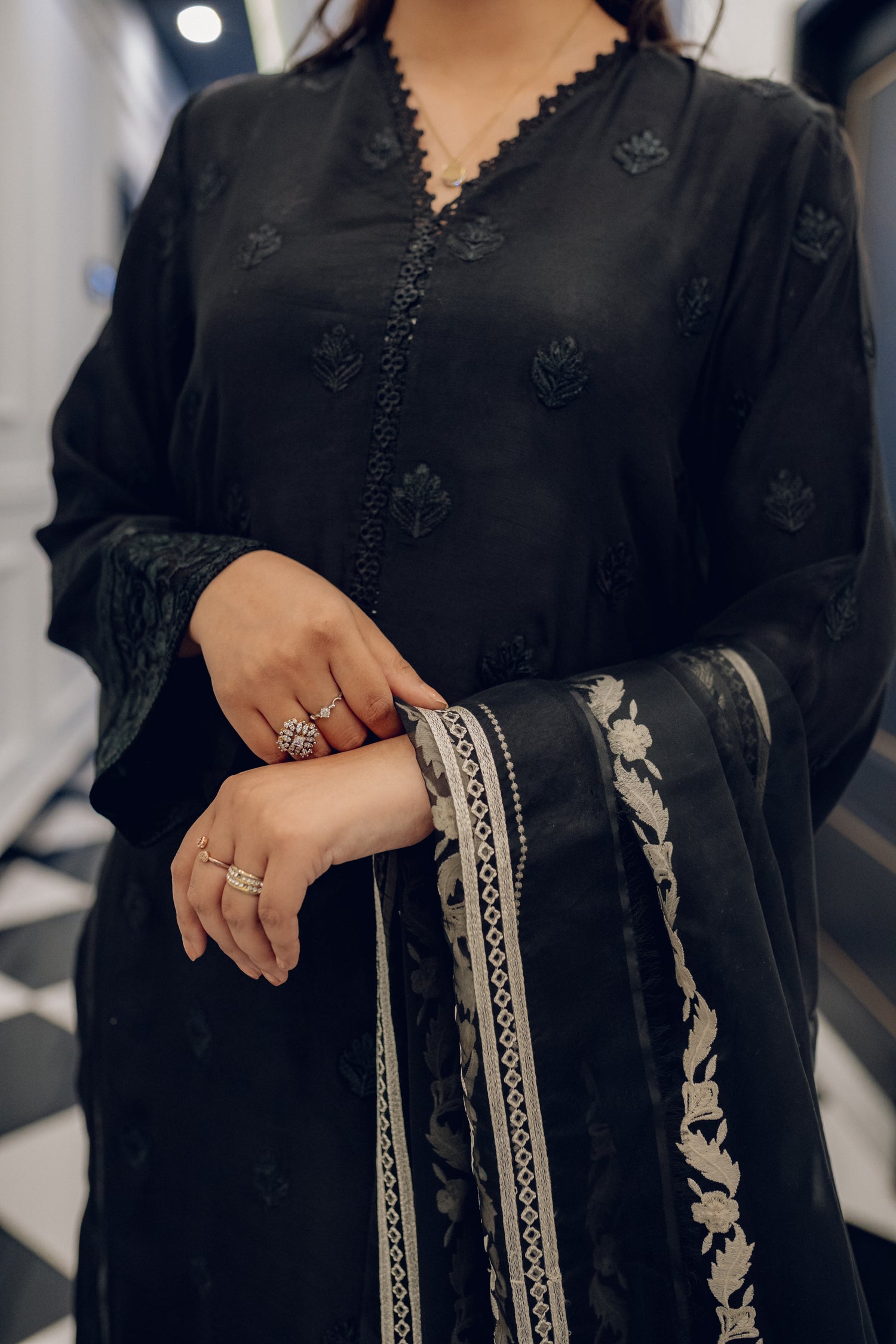 A sophisticated black embroidered dress with intricate motifs and lace detailing, paired with an organza dupatta featuring coordinated embroidery for an elegant look.