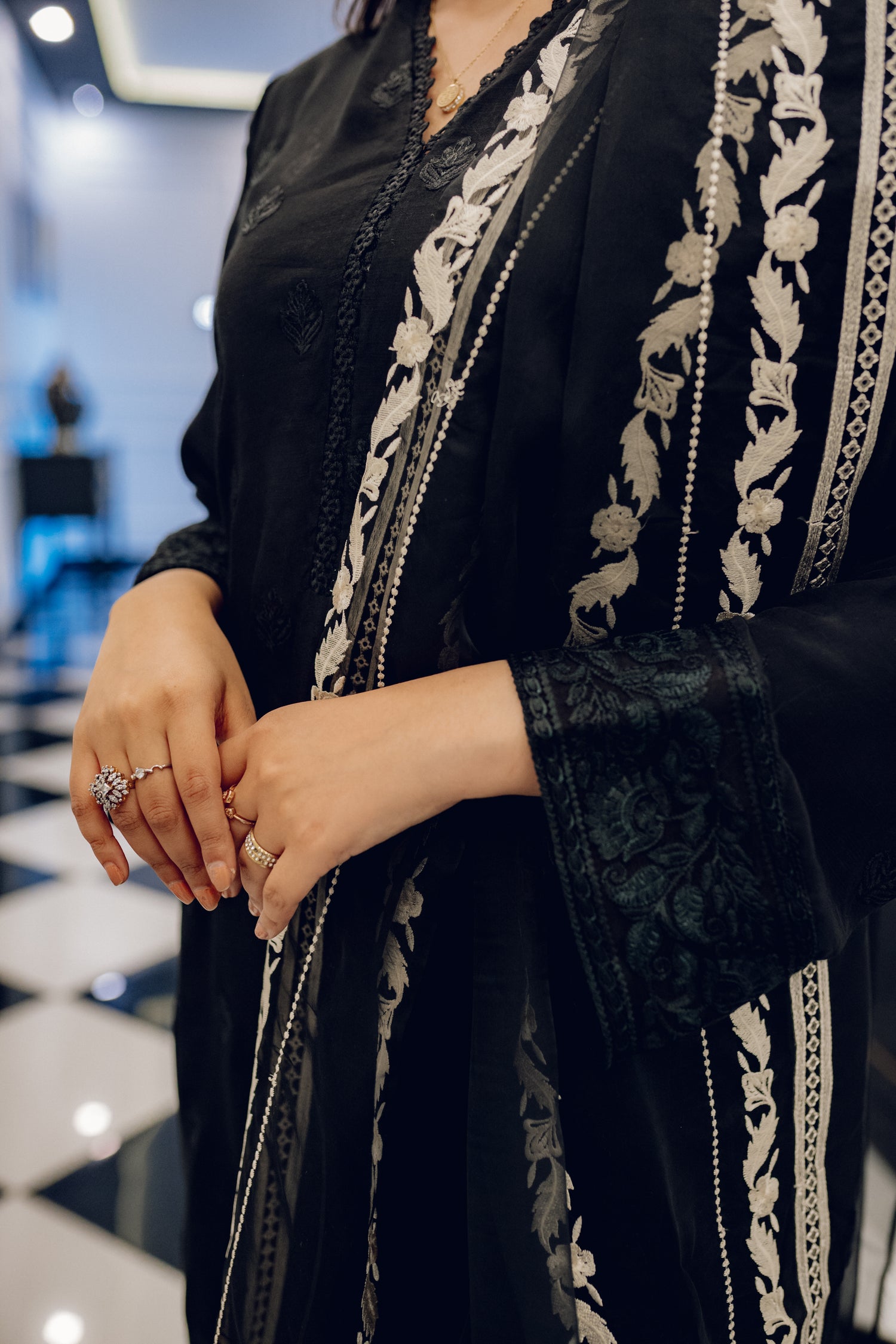 A sophisticated black embroidered dress with intricate motifs and lace detailing, paired with an organza dupatta featuring coordinated embroidery for an elegant look.
