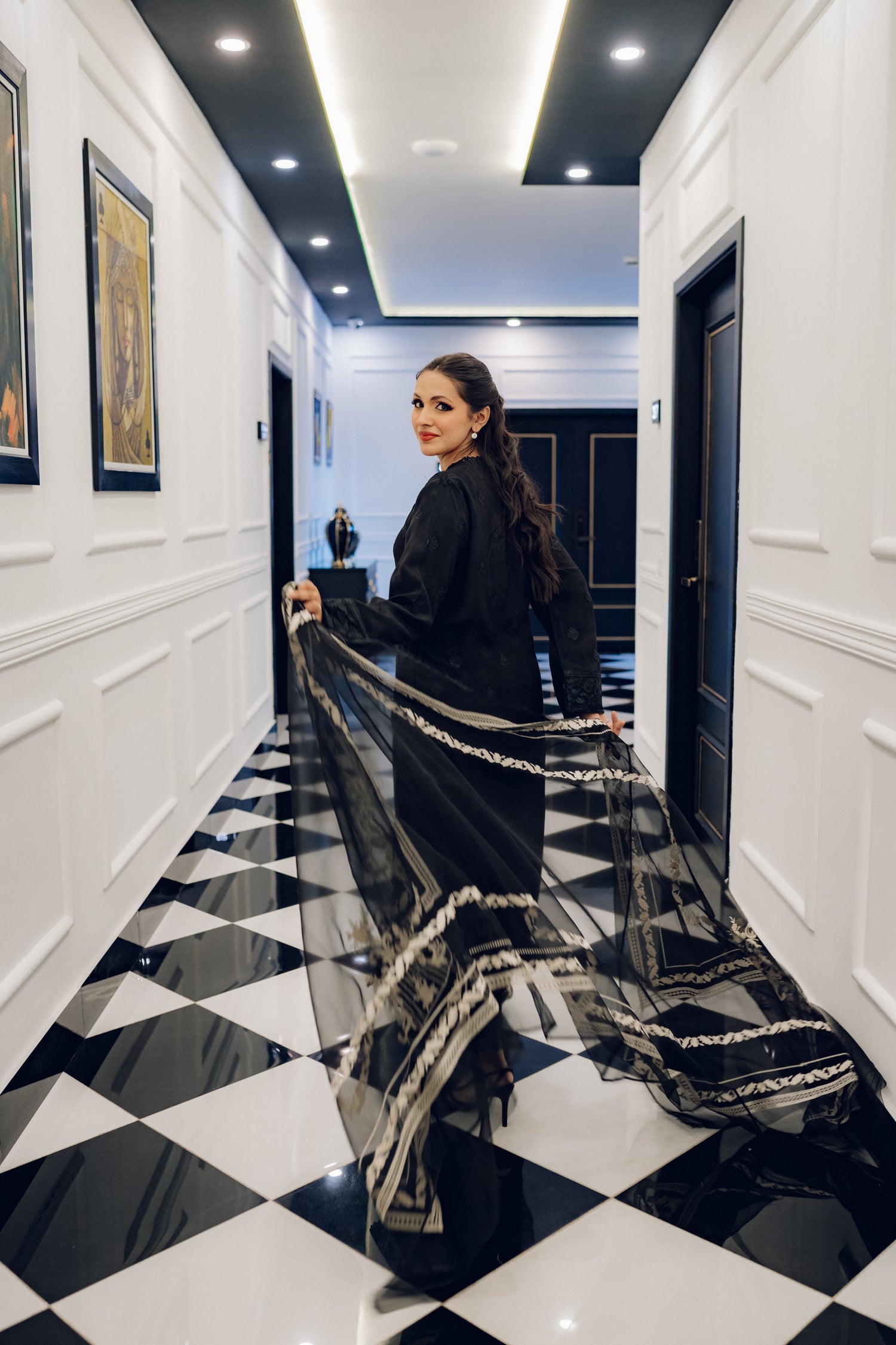 A sophisticated black embroidered dress with intricate motifs and lace detailing, paired with an organza dupatta featuring coordinated embroidery for an elegant look.