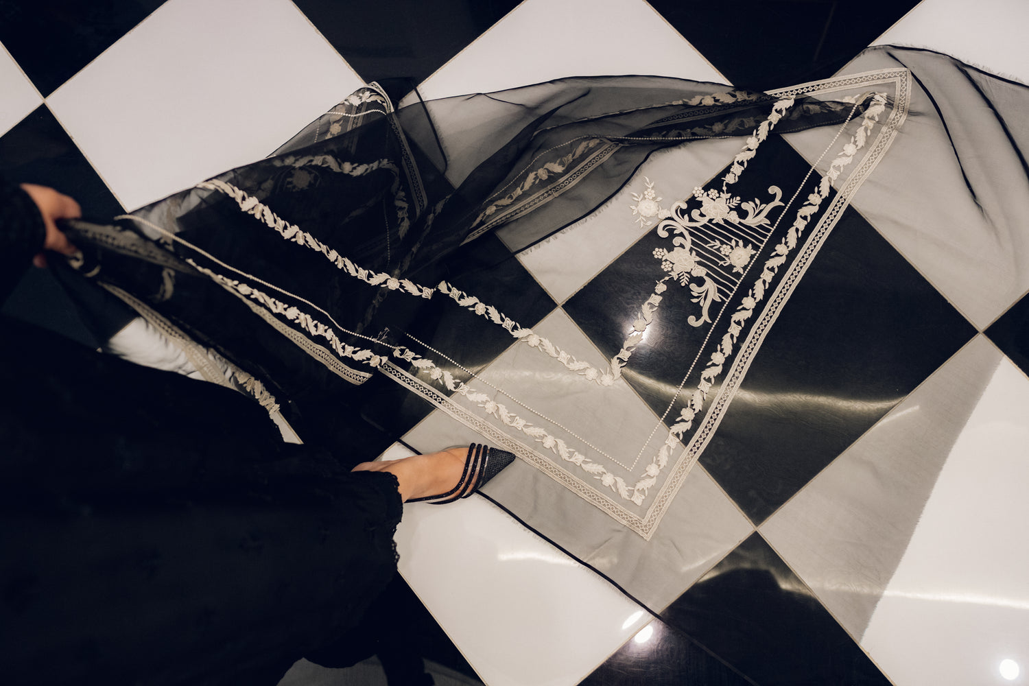 A sophisticated black embroidered dress with intricate motifs and lace detailing, paired with an organza dupatta featuring coordinated embroidery for an elegant look.