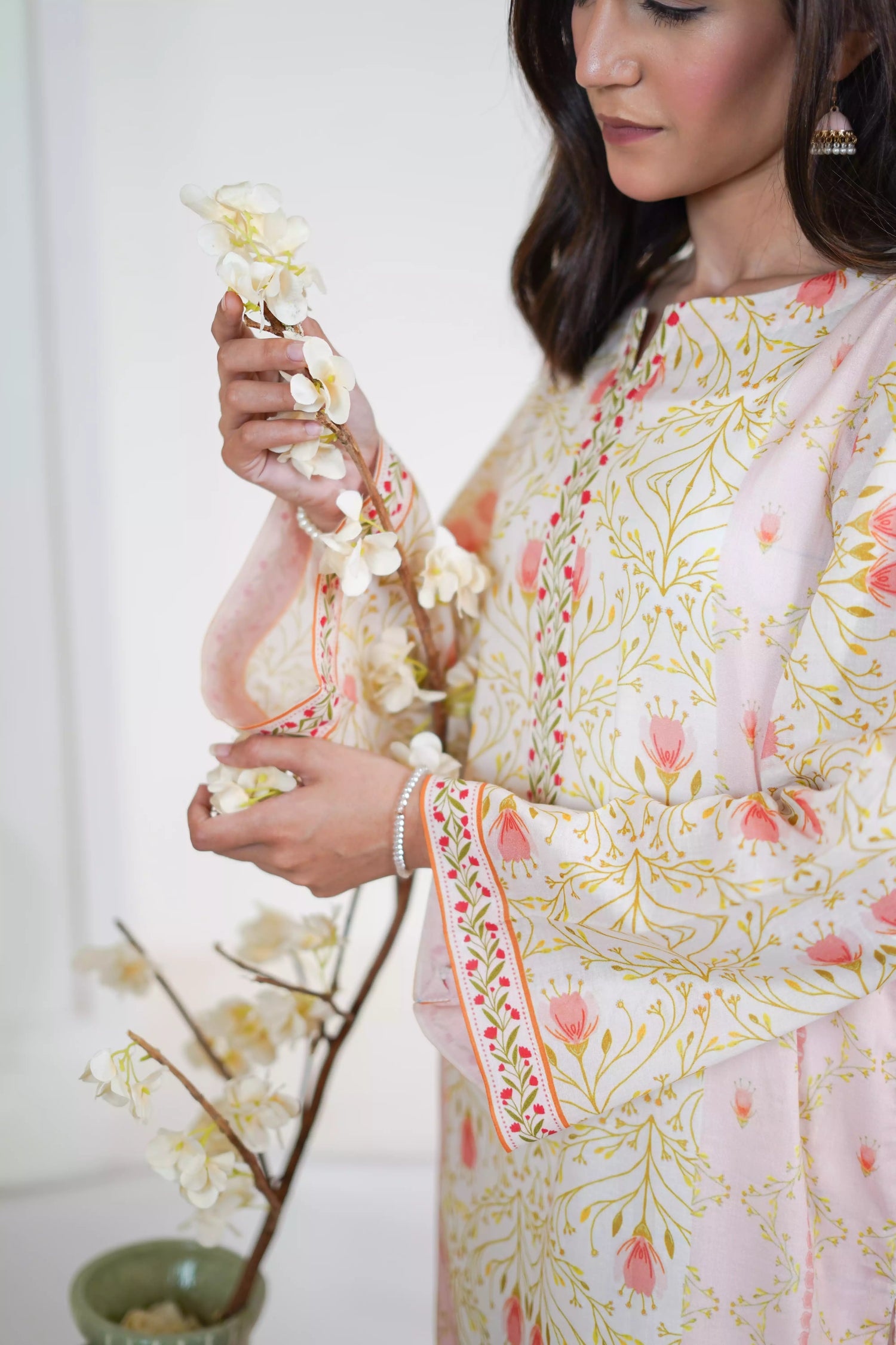 Elegant floral print with pink tulips and green vines on soft pastel fabric. Features fine borders and a graceful, symmetrical design for festive or casual wear.
