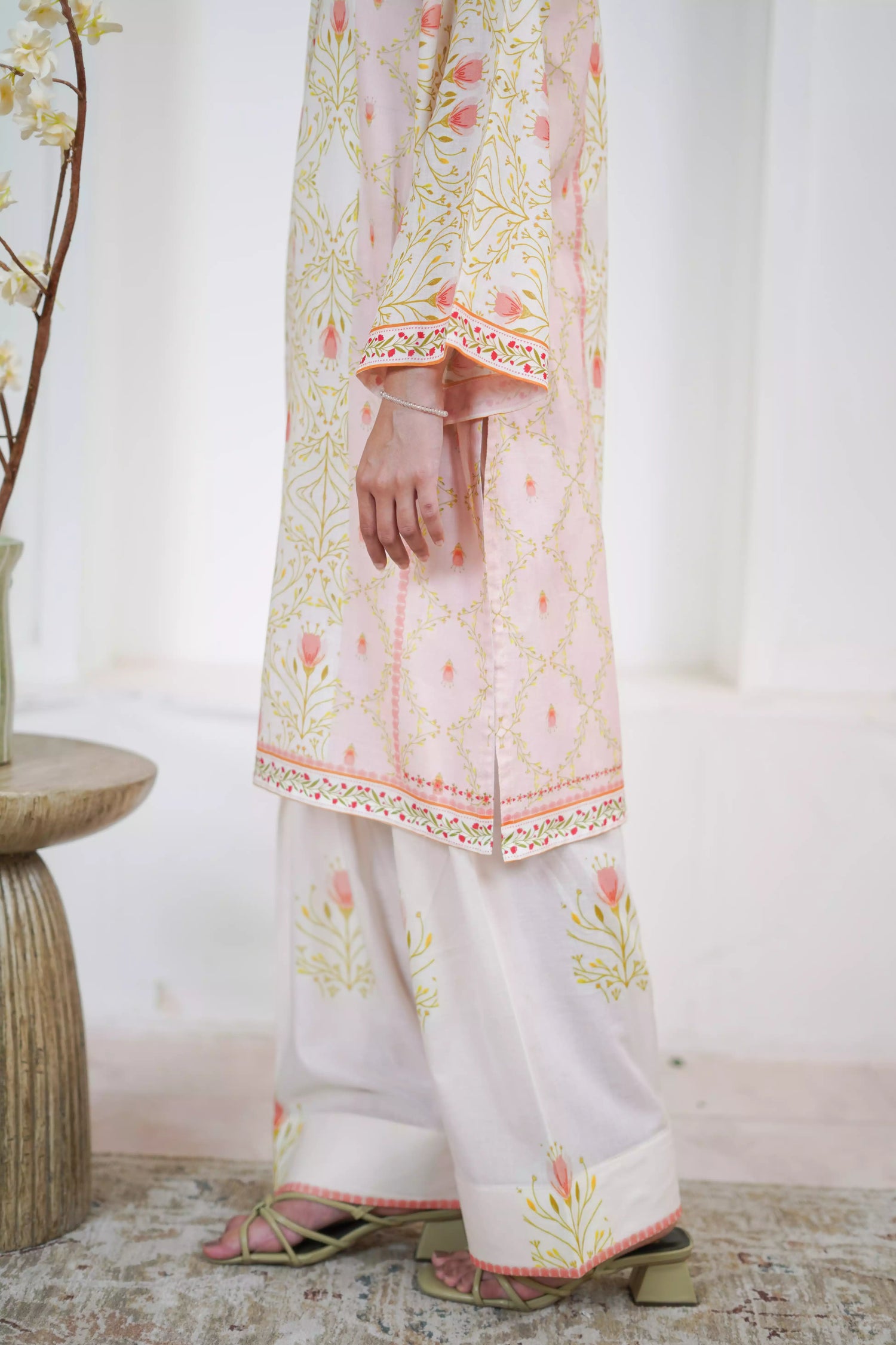 Elegant floral print with pink tulips and green vines on soft pastel fabric. Features fine borders and a graceful, symmetrical design for festive or casual wear.