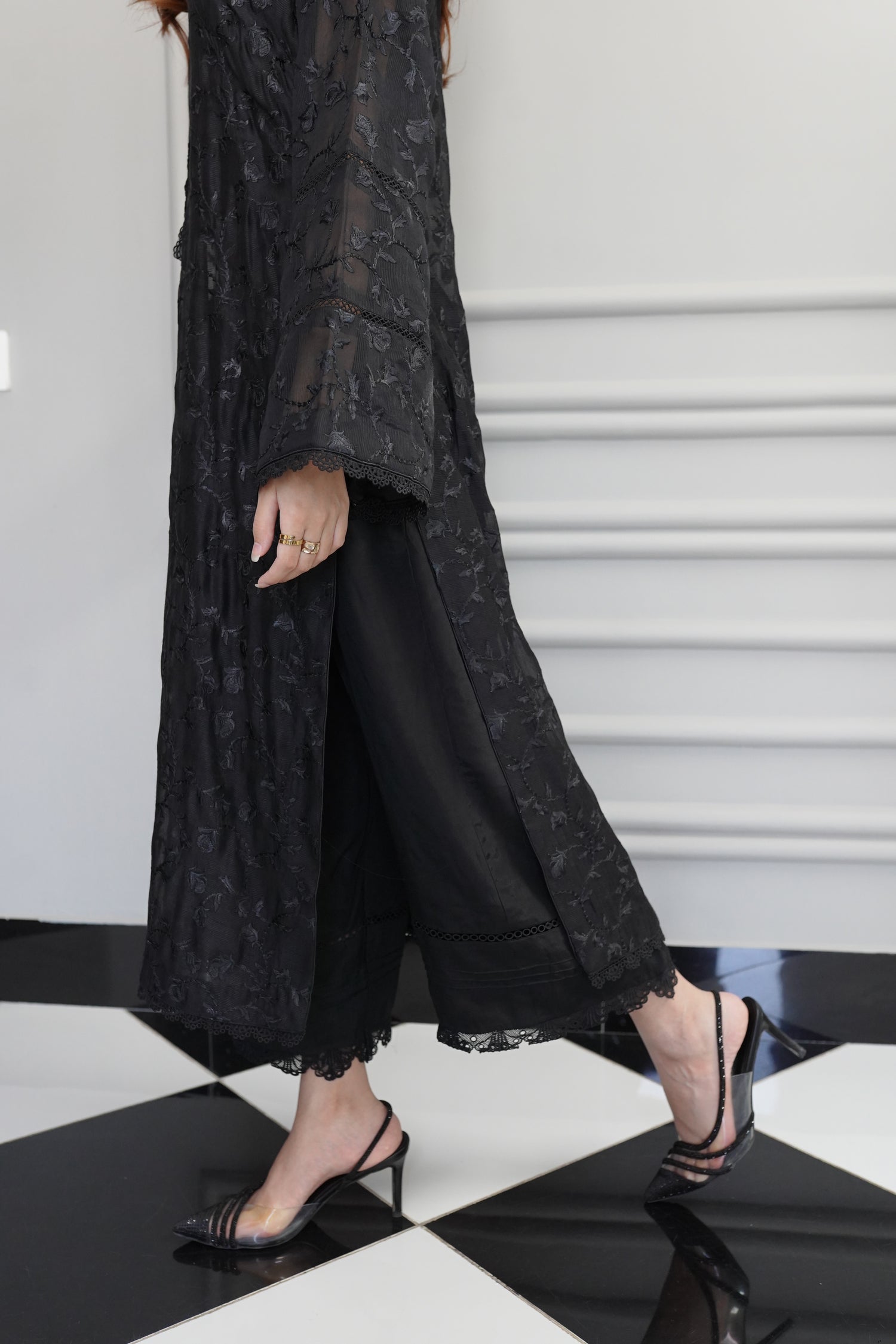 Black embroidered raw silk dress with lace-detailed neckline and sleeves, paired with matching flared pants, showcasing sophisticated craftsmanship and cohesive design.