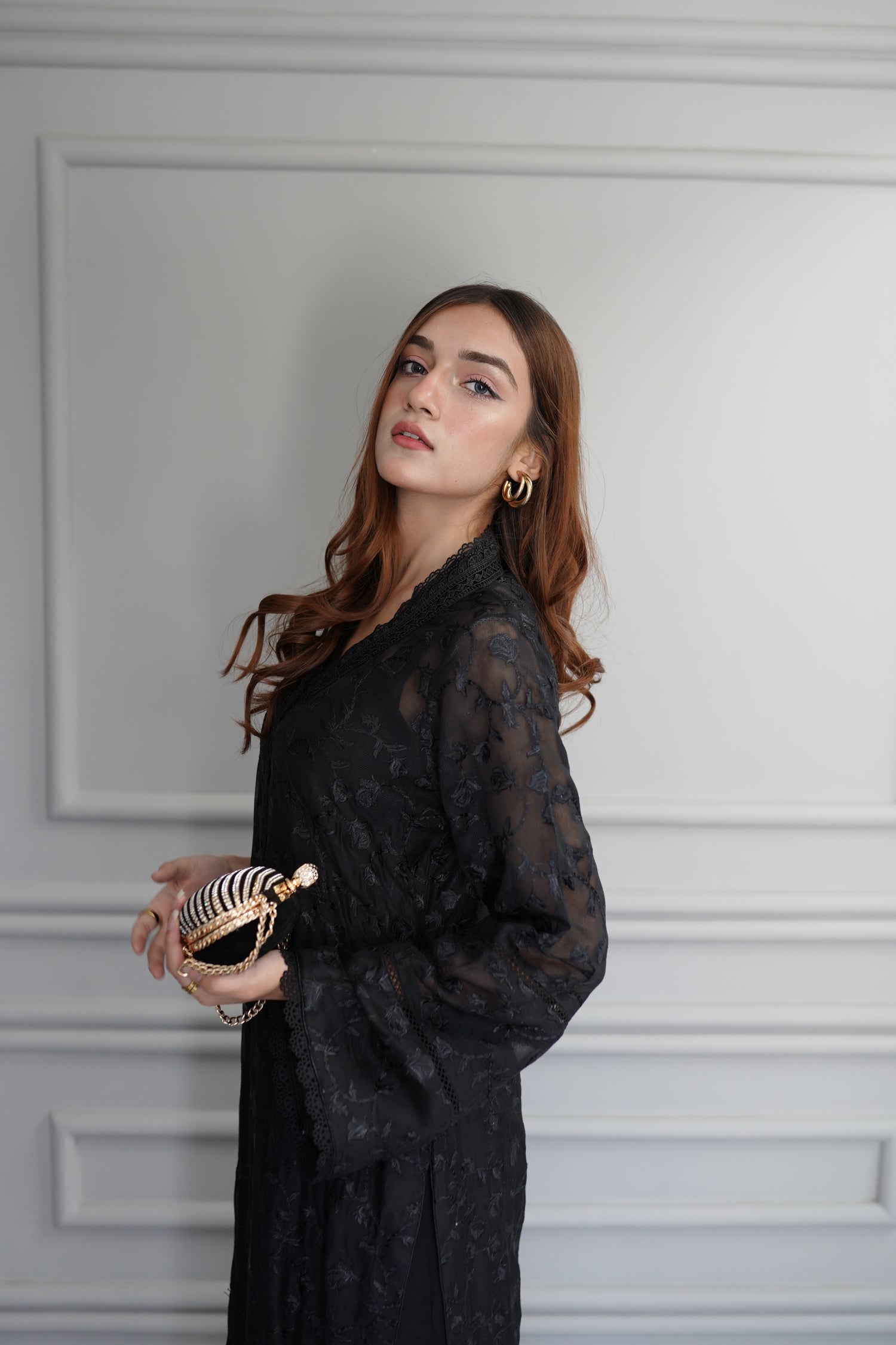 Black embroidered raw silk dress with lace-detailed neckline and sleeves, paired with matching flared pants, showcasing sophisticated craftsmanship and cohesive design.