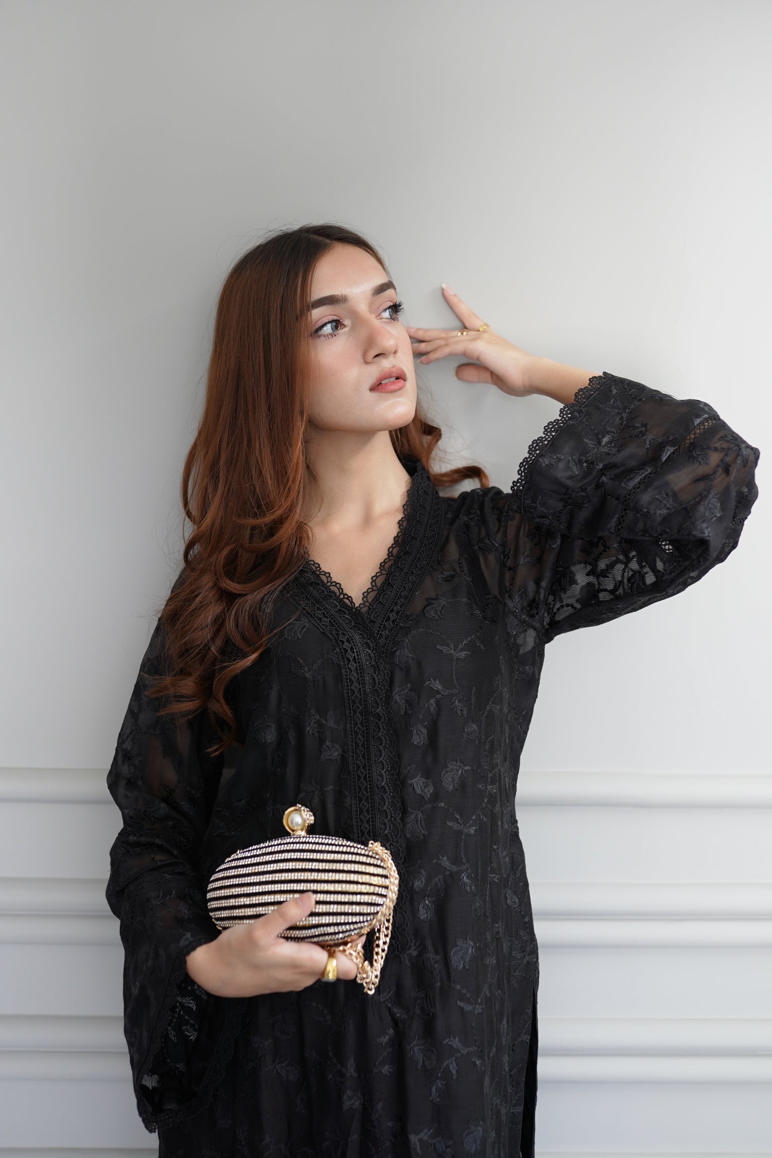 Black embroidered raw silk dress with lace-detailed neckline and sleeves, paired with matching flared pants, showcasing sophisticated craftsmanship and cohesive design.