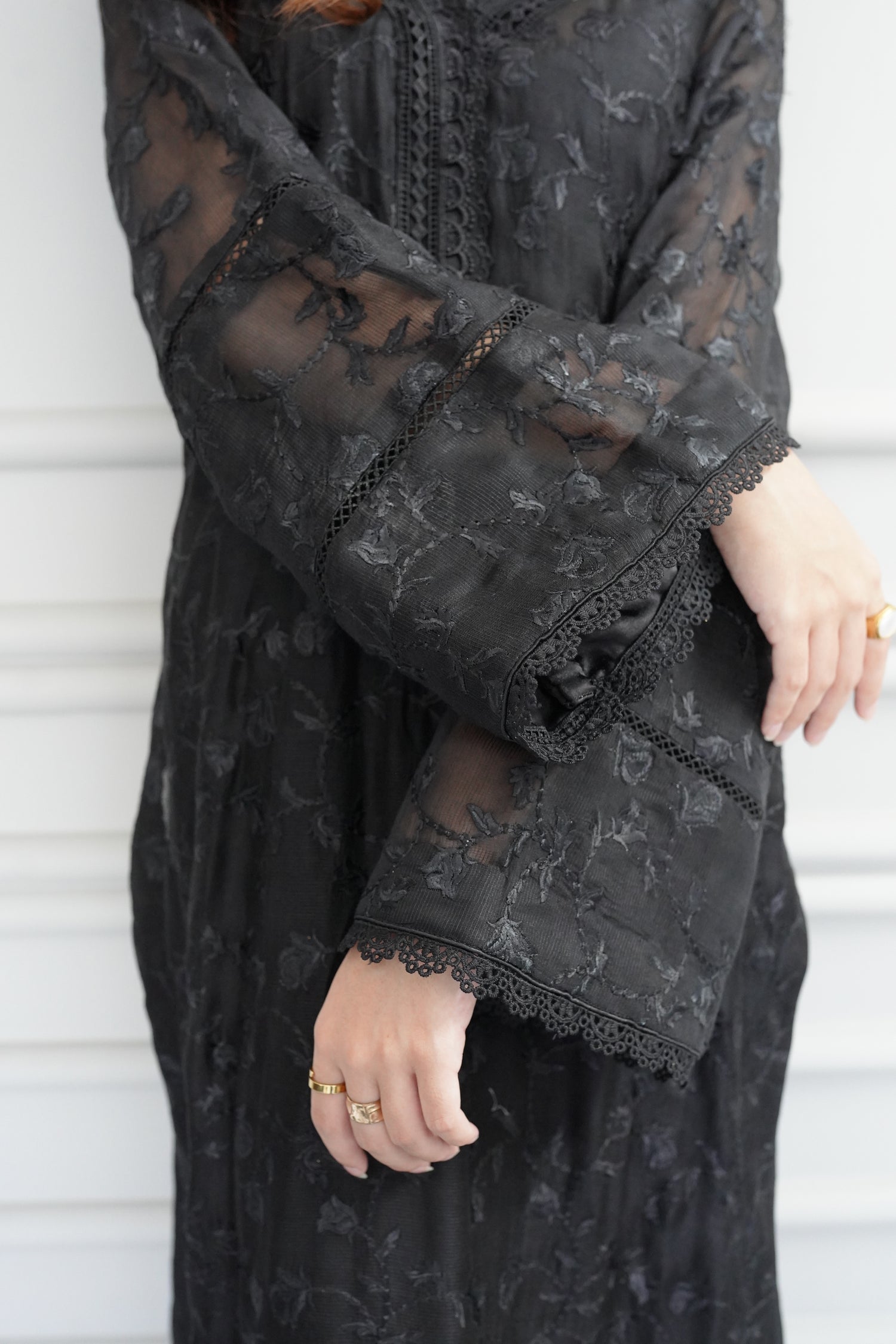 Black embroidered raw silk dress with lace-detailed neckline and sleeves, paired with matching flared pants, showcasing sophisticated craftsmanship and cohesive design.