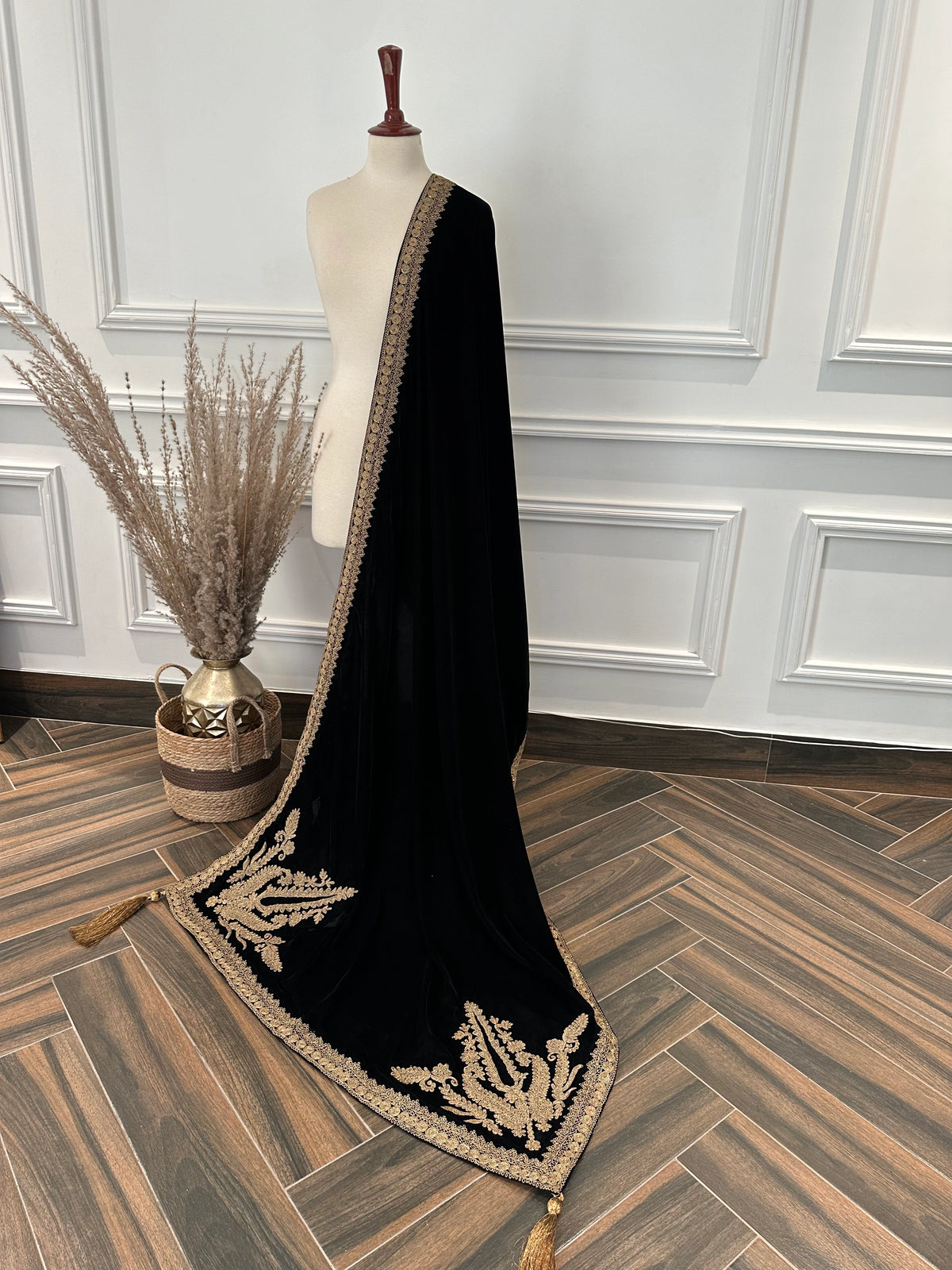 Luxurious black velvet shawl featuring detailed gold embroidery along the borders and corners, offering an elegant drape perfect for festive events and formal occasions.