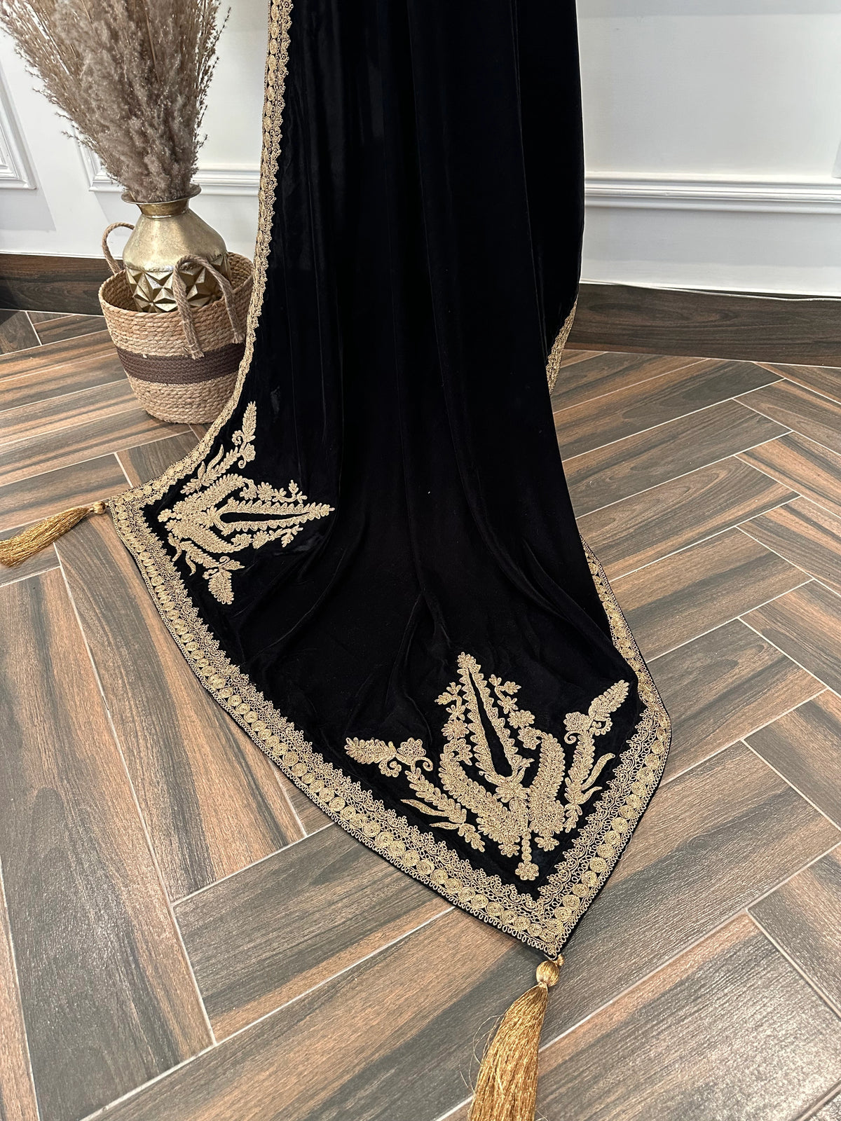 Luxurious black velvet shawl featuring detailed gold embroidery along the borders and corners, offering an elegant drape perfect for festive events and formal occasions.