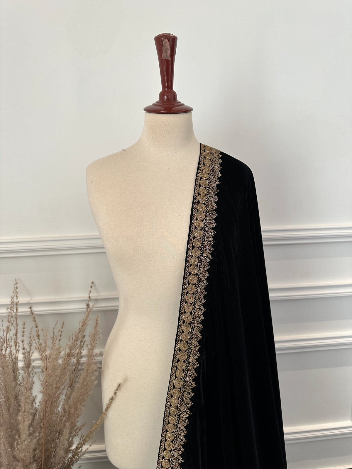 Luxurious black velvet shawl featuring detailed gold embroidery along the borders and corners, offering an elegant drape perfect for festive events and formal occasions.