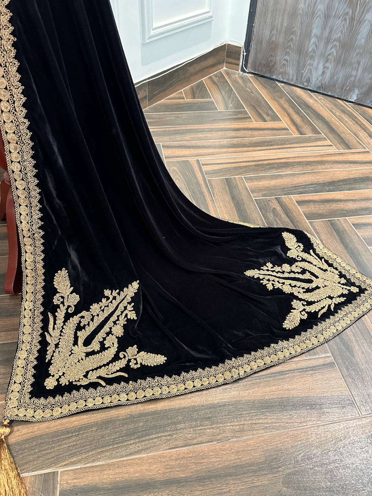 Luxurious black velvet shawl featuring detailed gold embroidery along the borders and corners, offering an elegant drape perfect for festive events and formal occasions.
