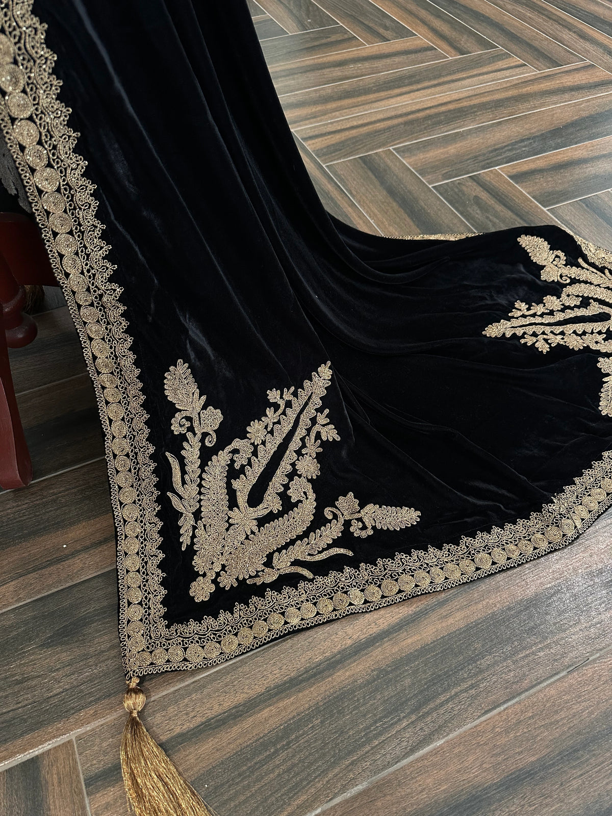 Luxurious black velvet shawl featuring detailed gold embroidery along the borders and corners, offering an elegant drape perfect for festive events and formal occasions.