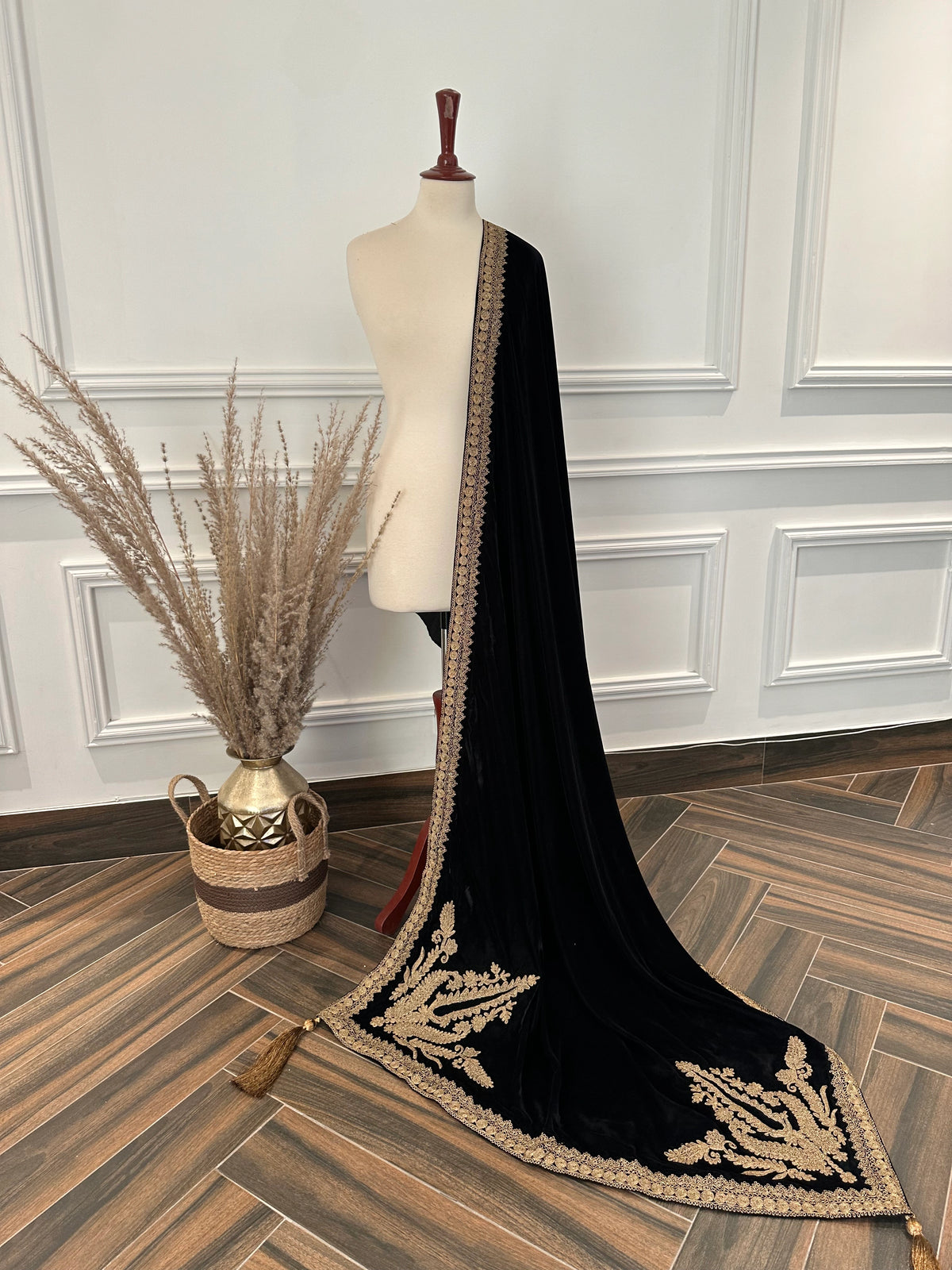 Luxurious black velvet shawl featuring detailed gold embroidery along the borders and corners, offering an elegant drape perfect for festive events and formal occasions.