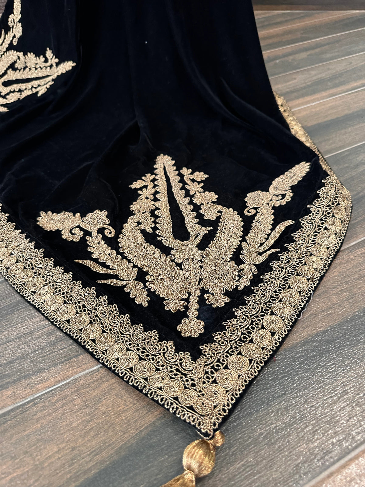 Luxurious black velvet shawl featuring detailed gold embroidery along the borders and corners, offering an elegant drape perfect for festive events and formal occasions.