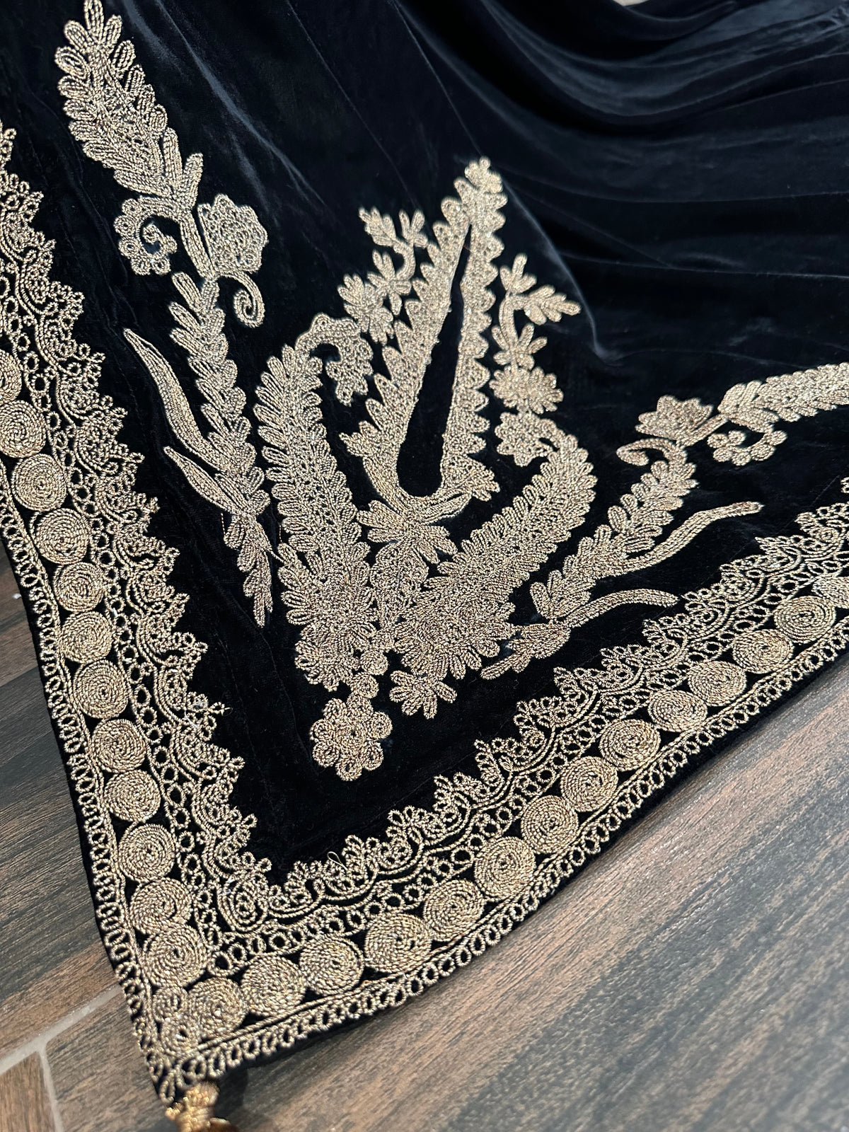 Luxurious black velvet shawl featuring detailed gold embroidery along the borders and corners, offering an elegant drape perfect for festive events and formal occasions.