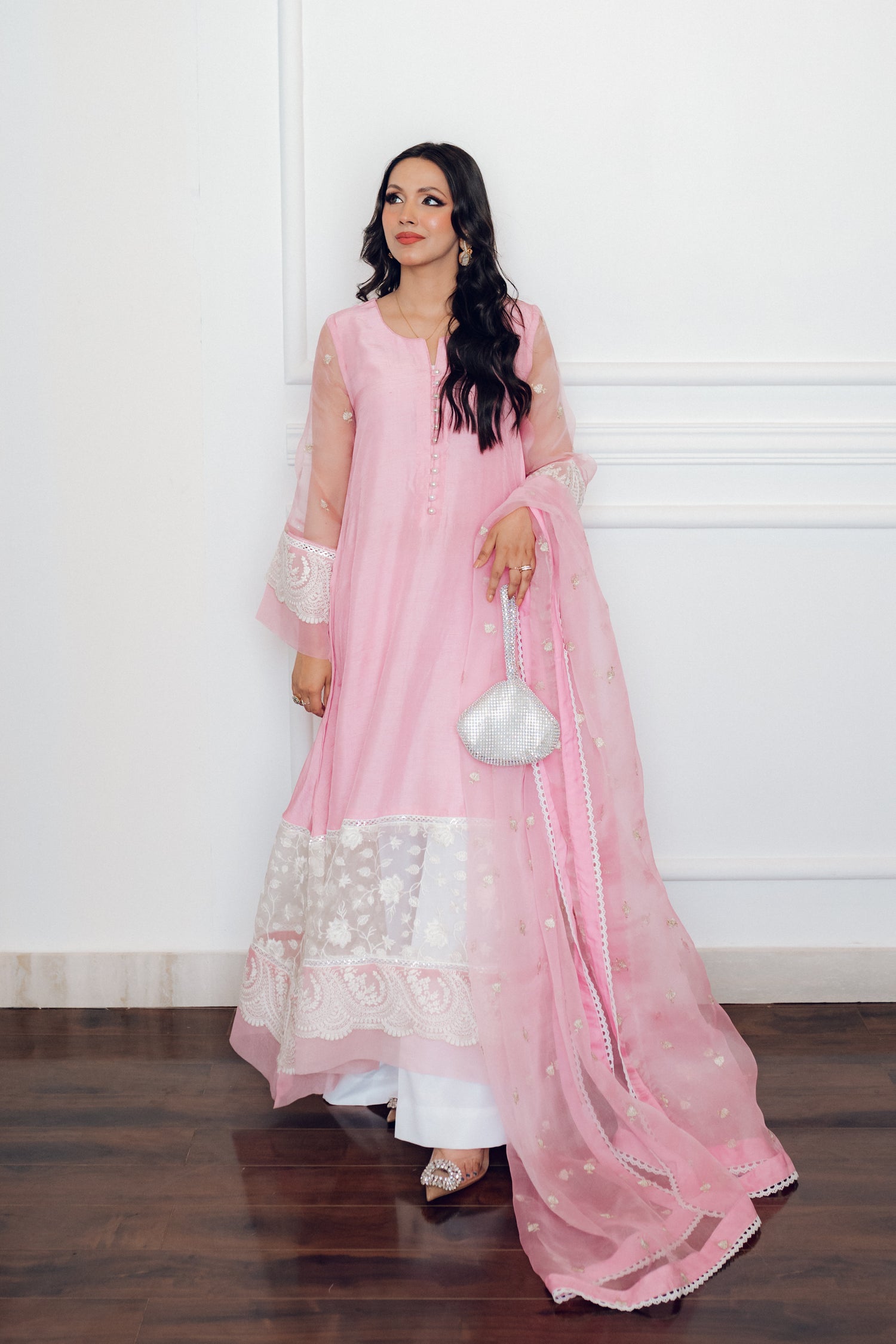 A delicate pink dress adorned with lace and pearl buttons, exuding romance and timeless sophistication.