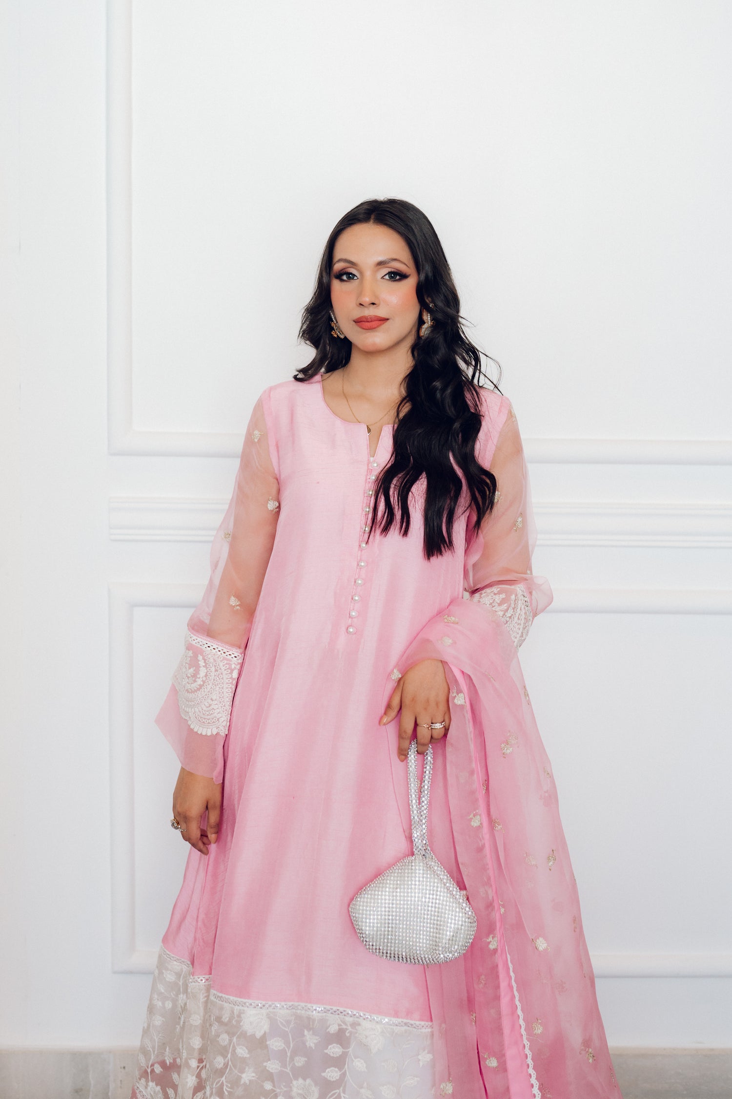 A delicate pink dress adorned with lace and pearl buttons, exuding romance and timeless sophistication.