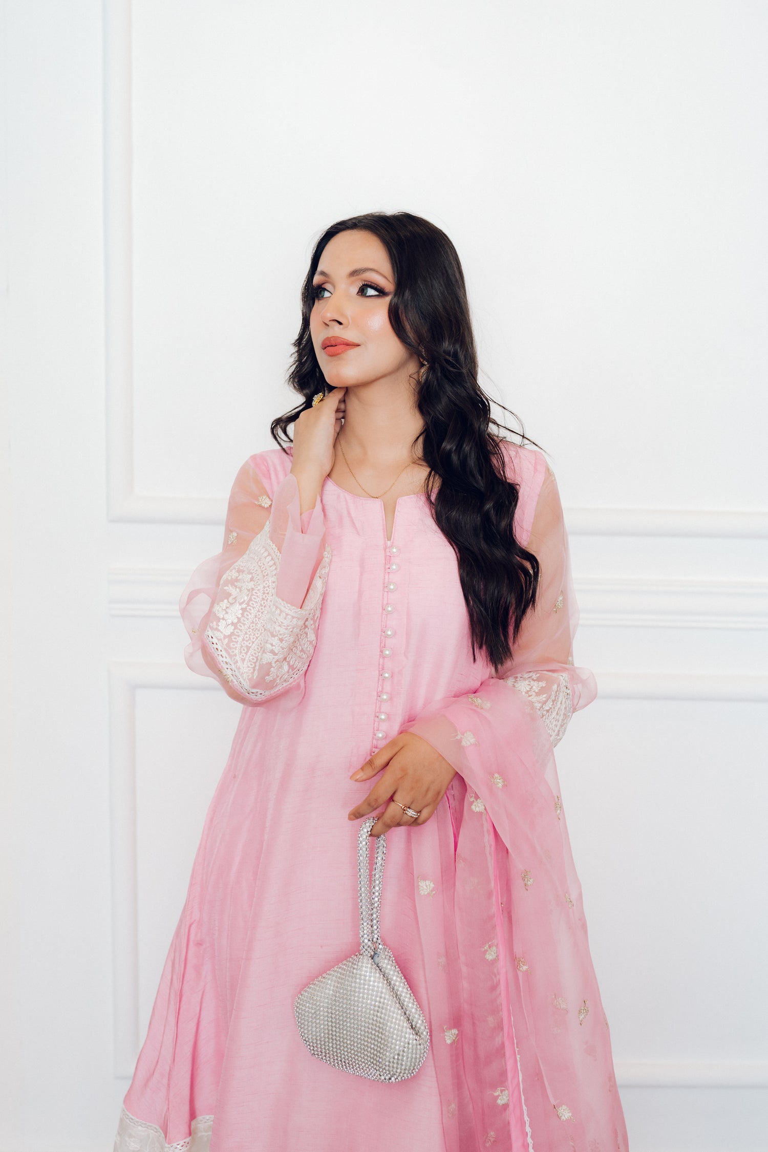 A delicate pink dress adorned with lace and pearl buttons, exuding romance and timeless sophistication.