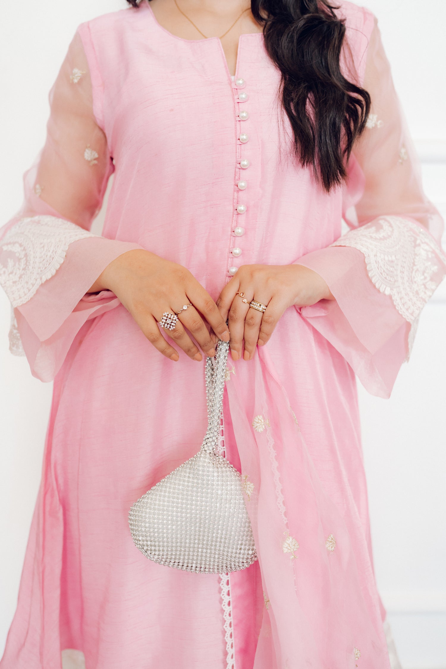 A delicate pink dress adorned with lace and pearl buttons, exuding romance and timeless sophistication.