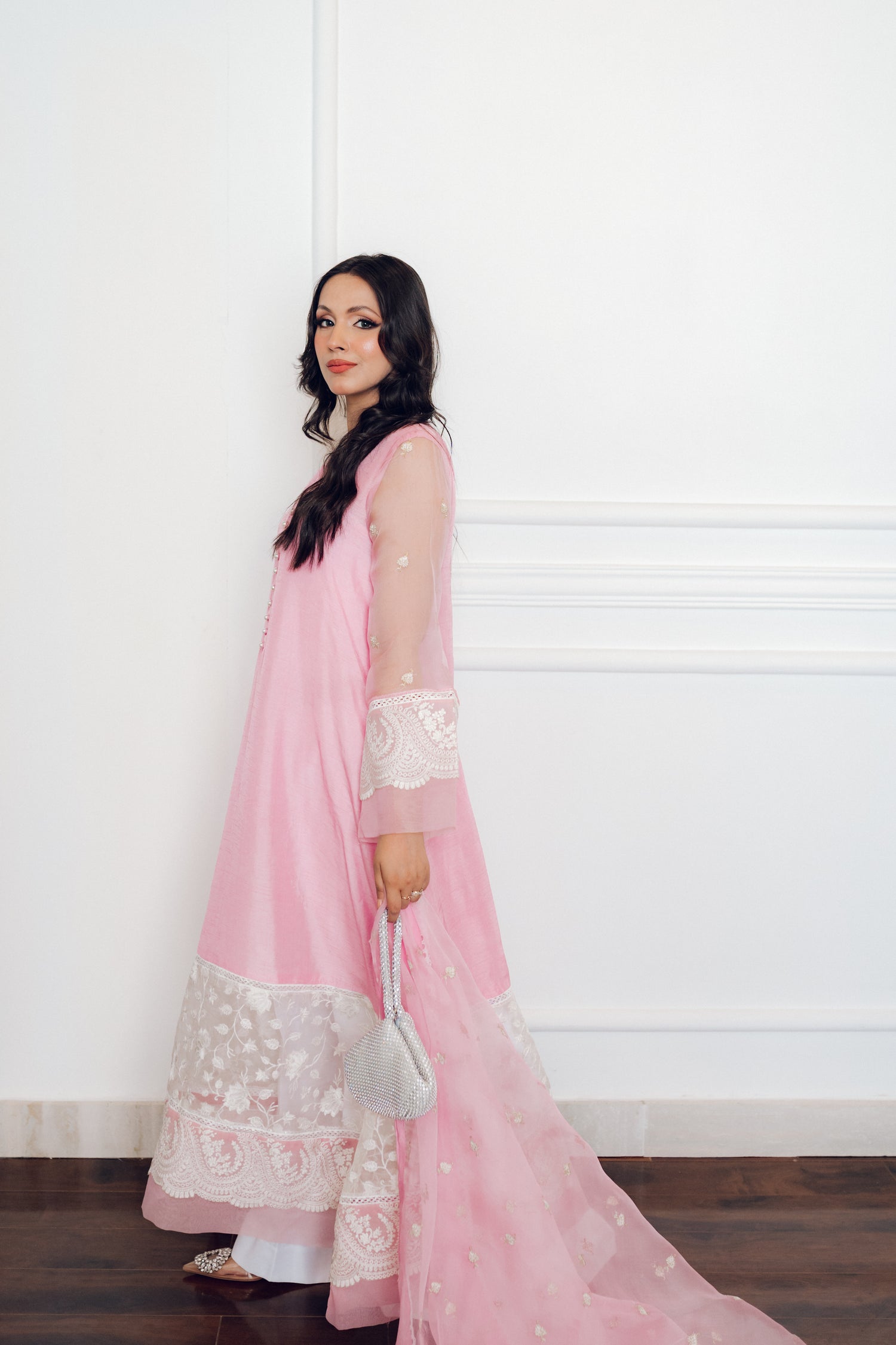 A delicate pink dress adorned with lace and pearl buttons, exuding romance and timeless sophistication.
