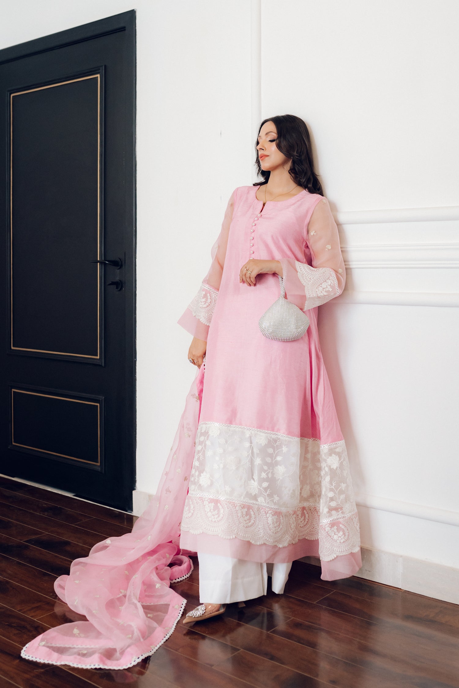 A delicate pink dress adorned with lace and pearl buttons, exuding romance and timeless sophistication.
