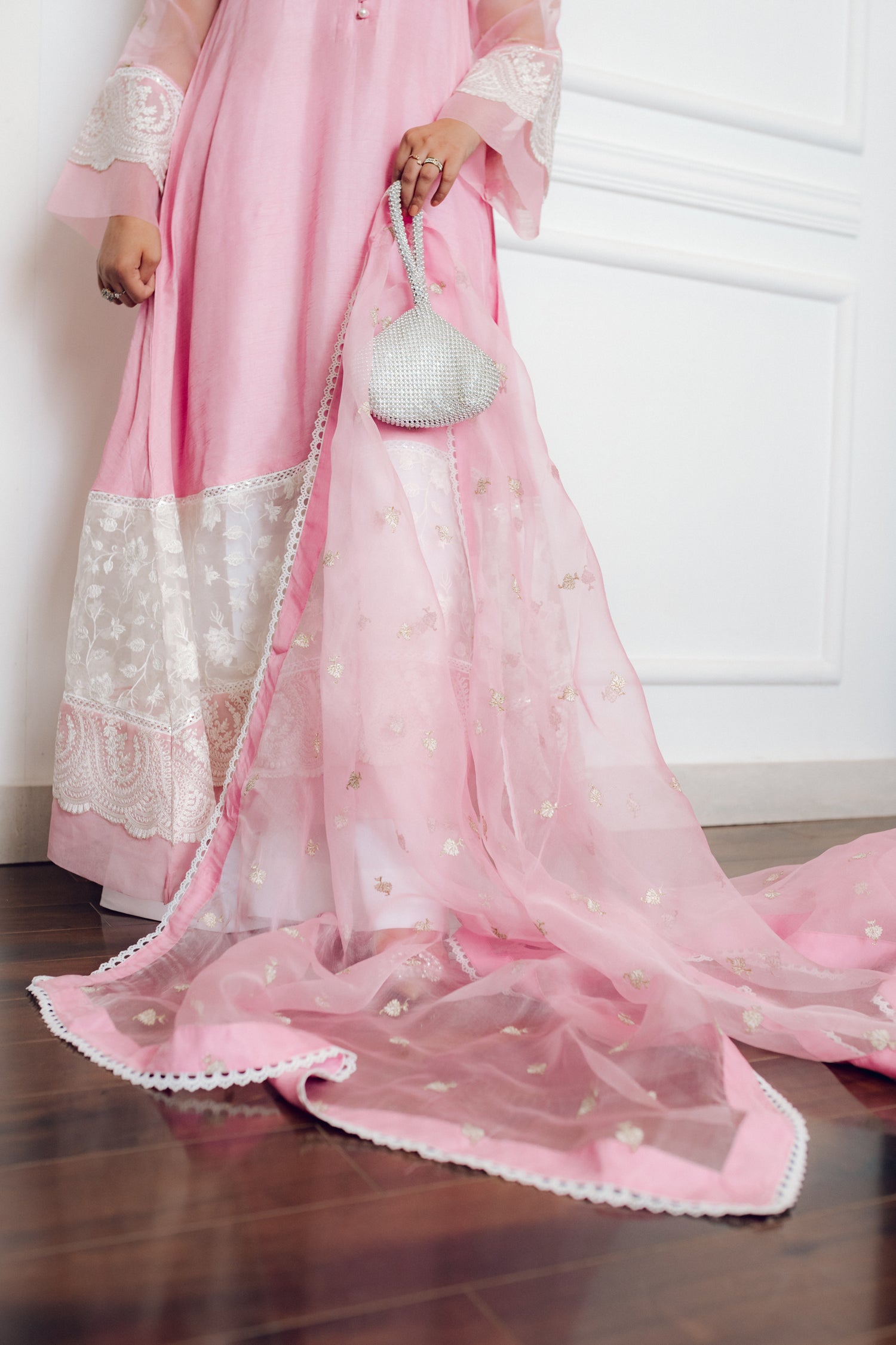 A delicate pink dress adorned with lace and pearl buttons, exuding romance and timeless sophistication.