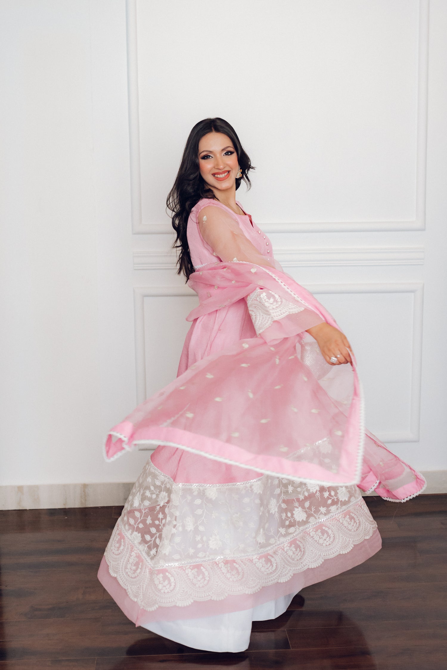 A delicate pink dress adorned with lace and pearl buttons, exuding romance and timeless sophistication.