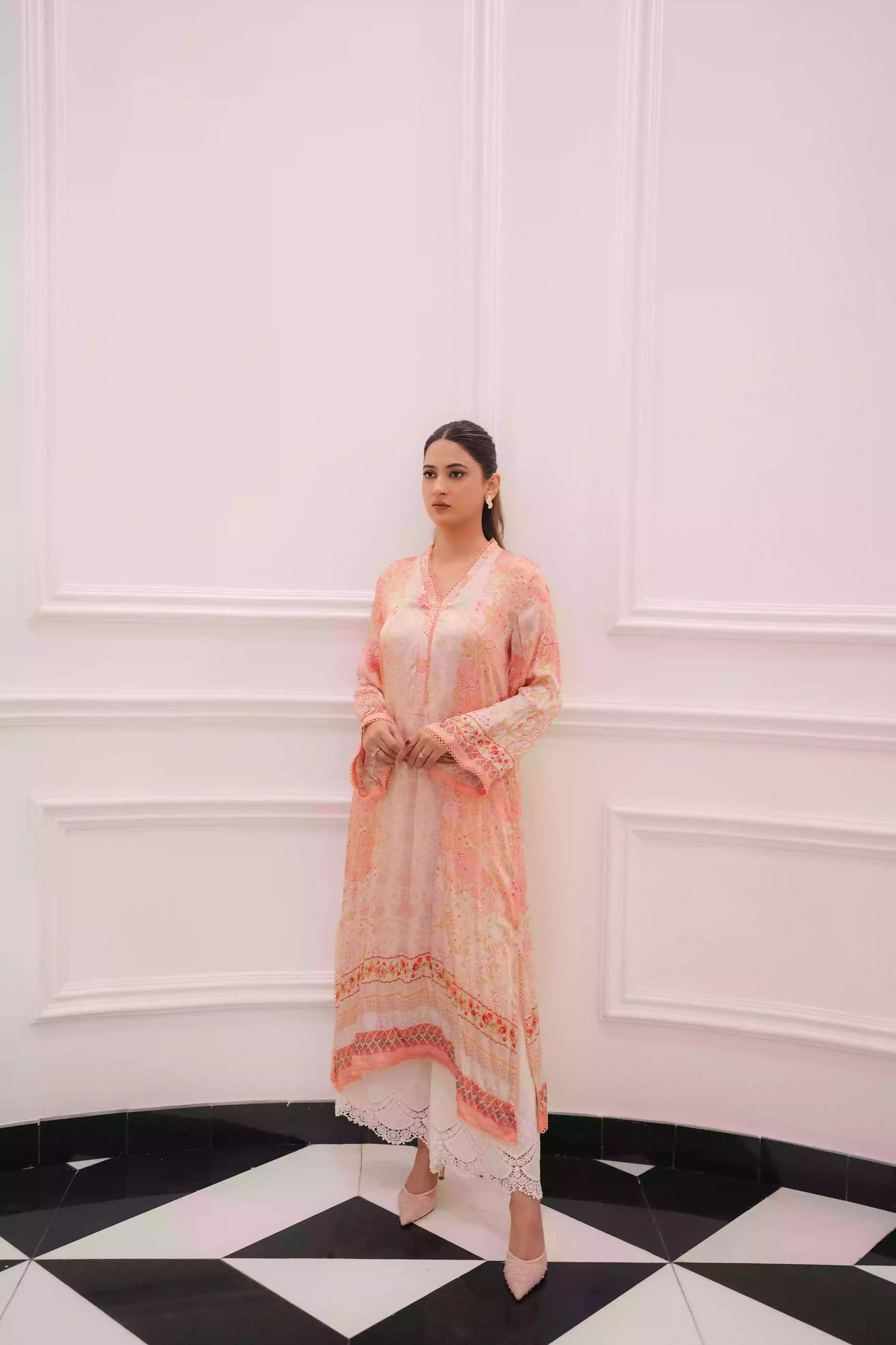 Discover two-tone pastel peach silk kurta featuring a delicate floral digital print and a flowing draped silhouette. The design is detailed with subtle lace accents along the neckline and hem, offering a soft, feminine look suitable for  festive gatherings, and semi-formal occasions.