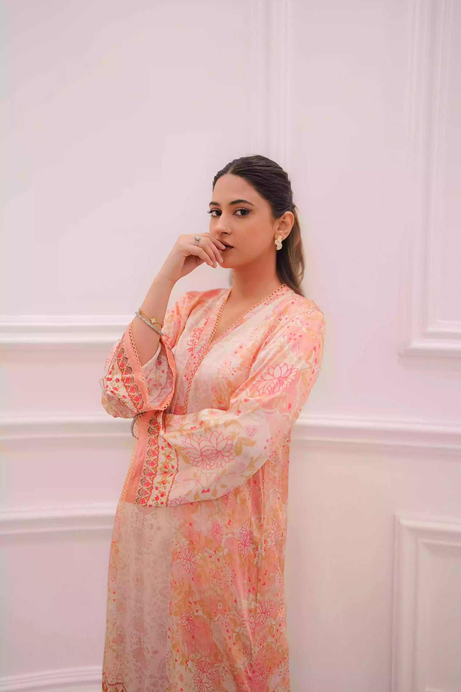 Discover two-tone pastel peach silk kurta featuring a delicate floral digital print and a flowing draped silhouette. The design is detailed with subtle lace accents along the neckline and hem, offering a soft, feminine look suitable for  festive gatherings, and semi-formal occasions.