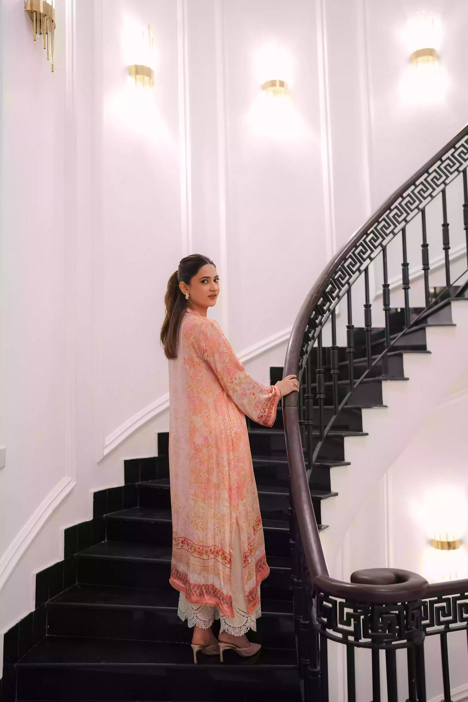 Discover two-tone pastel peach silk kurta featuring a delicate floral digital print and a flowing draped silhouette. The design is detailed with subtle lace accents along the neckline and hem, offering a soft, feminine look suitable for  festive gatherings, and semi-formal occasions.