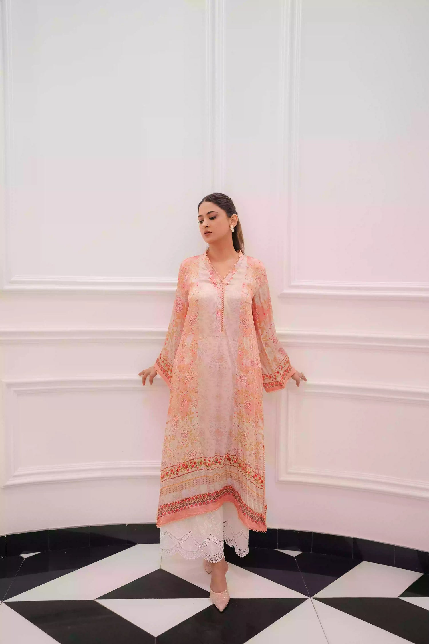 Discover two-tone pastel peach silk kurta featuring a delicate floral digital print and a flowing draped silhouette. The design is detailed with subtle lace accents along the neckline and hem, offering a soft, feminine look suitable for  festive gatherings, and semi-formal occasions.