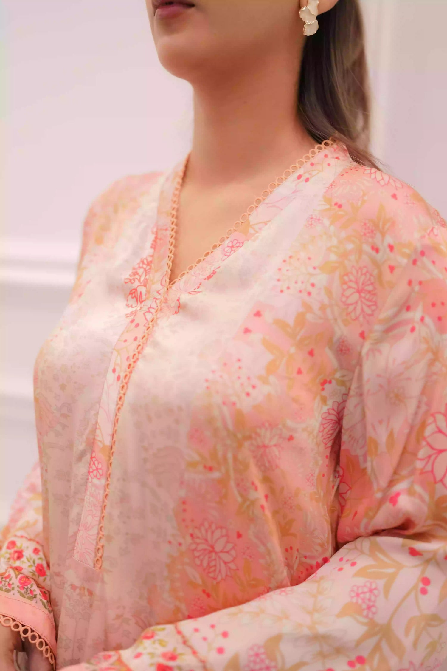 Discover two-tone pastel peach silk kurta featuring a delicate floral digital print and a flowing draped silhouette. The design is detailed with subtle lace accents along the neckline and hem, offering a soft, feminine look suitable for  festive gatherings, and semi-formal occasions.