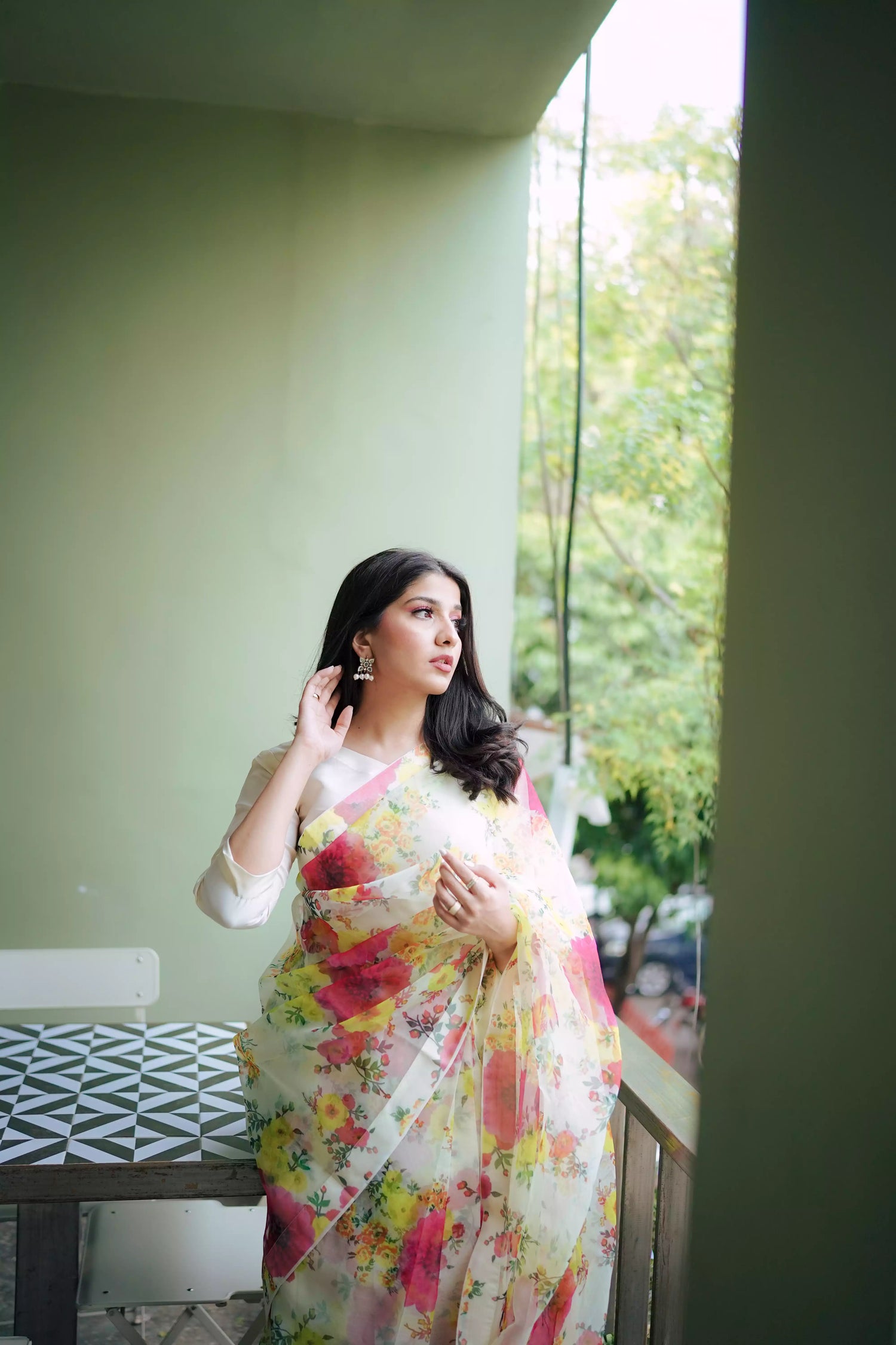 Cream floral printed organza saree with soft pastel patterns, paired with a matching Katan raw silk blouse and cotton petticoat; elegant drape ideal for festive and semi-formal occasions.