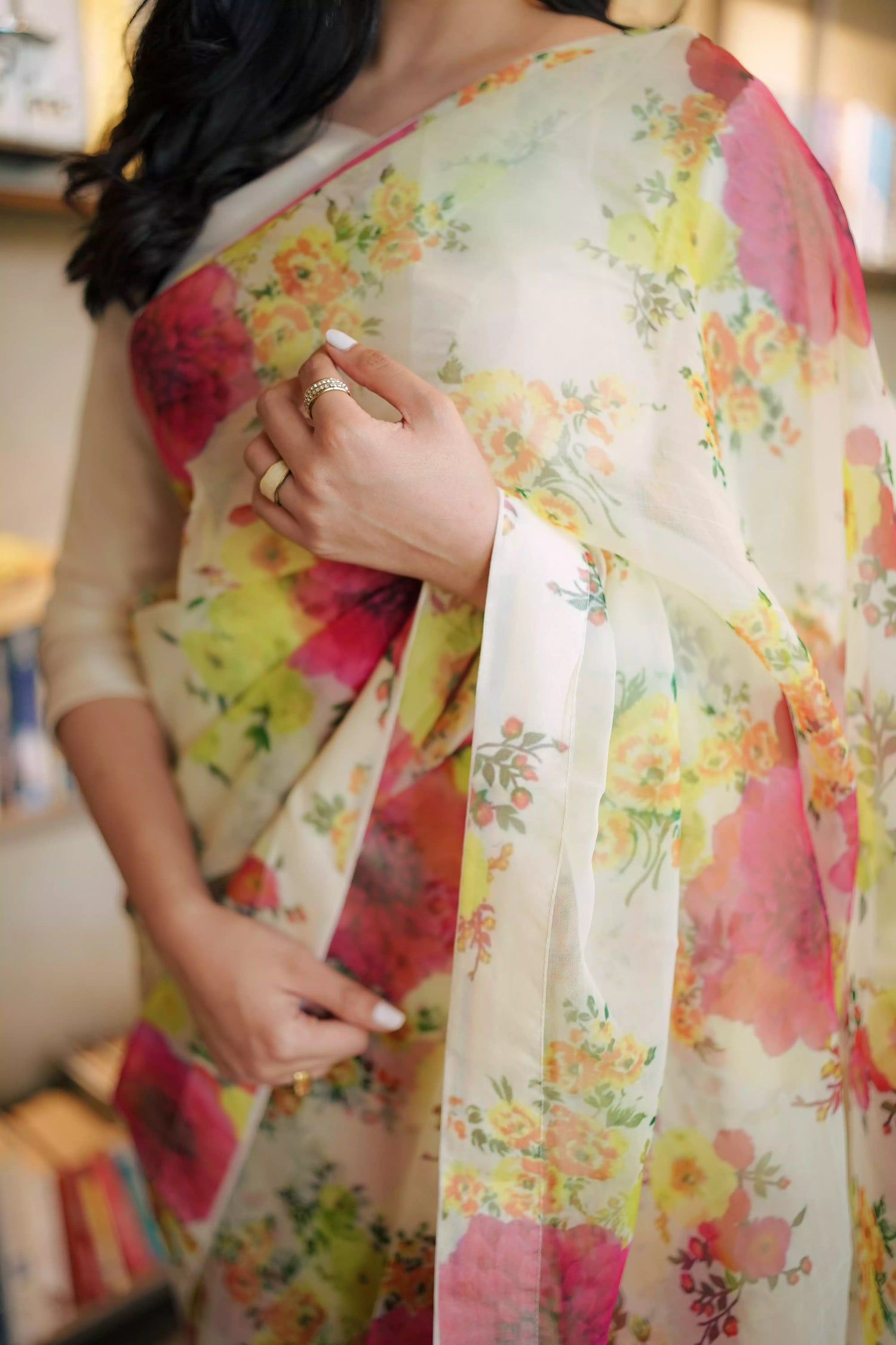 Cream floral printed organza saree with soft pastel patterns, paired with a matching Katan raw silk blouse and cotton petticoat; elegant drape ideal for festive and semi-formal occasions.