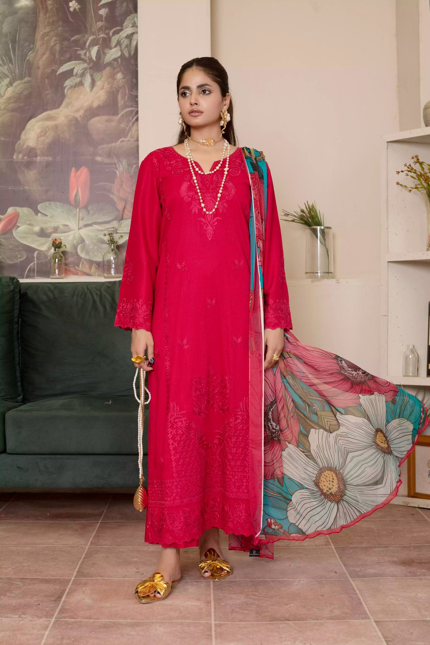 A deep red three piece suit complemented by a teal and pink floral dupatta, perfect for festive charm.
