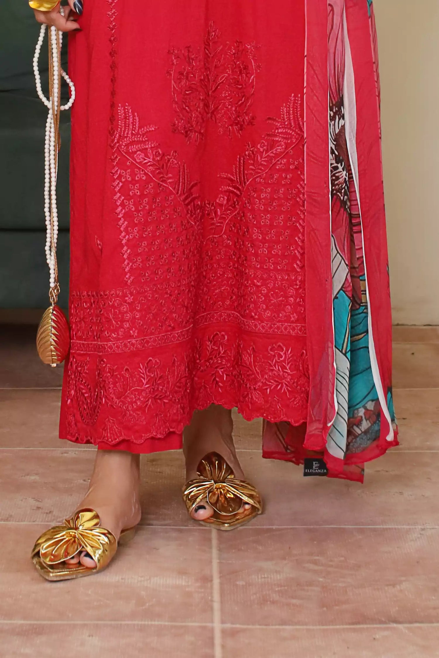 A deep red three piece suit complemented by a teal and pink floral dupatta, perfect for festive charm.
