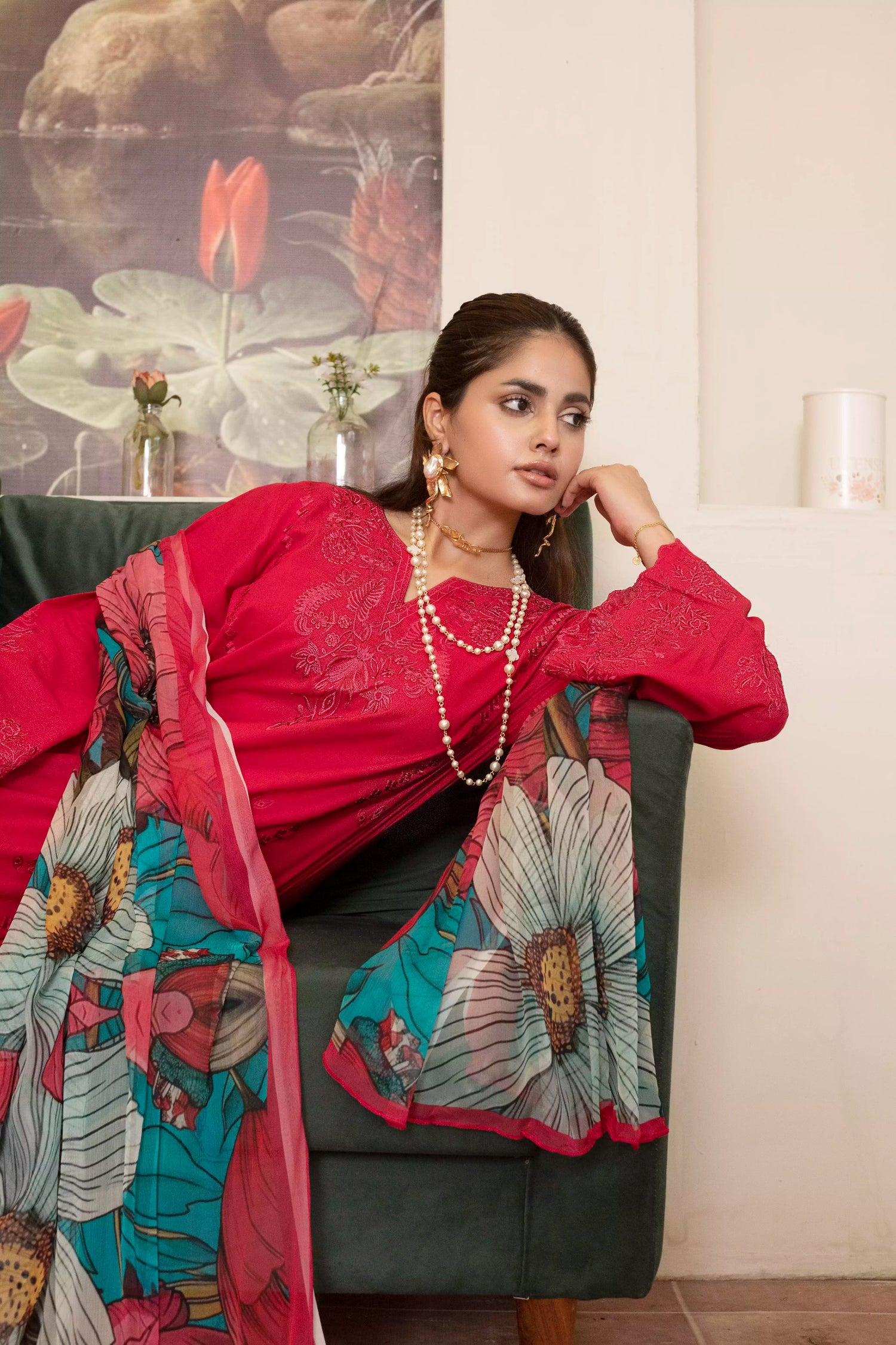 A deep red three piece suit complemented by a teal and pink floral dupatta, perfect for festive charm.