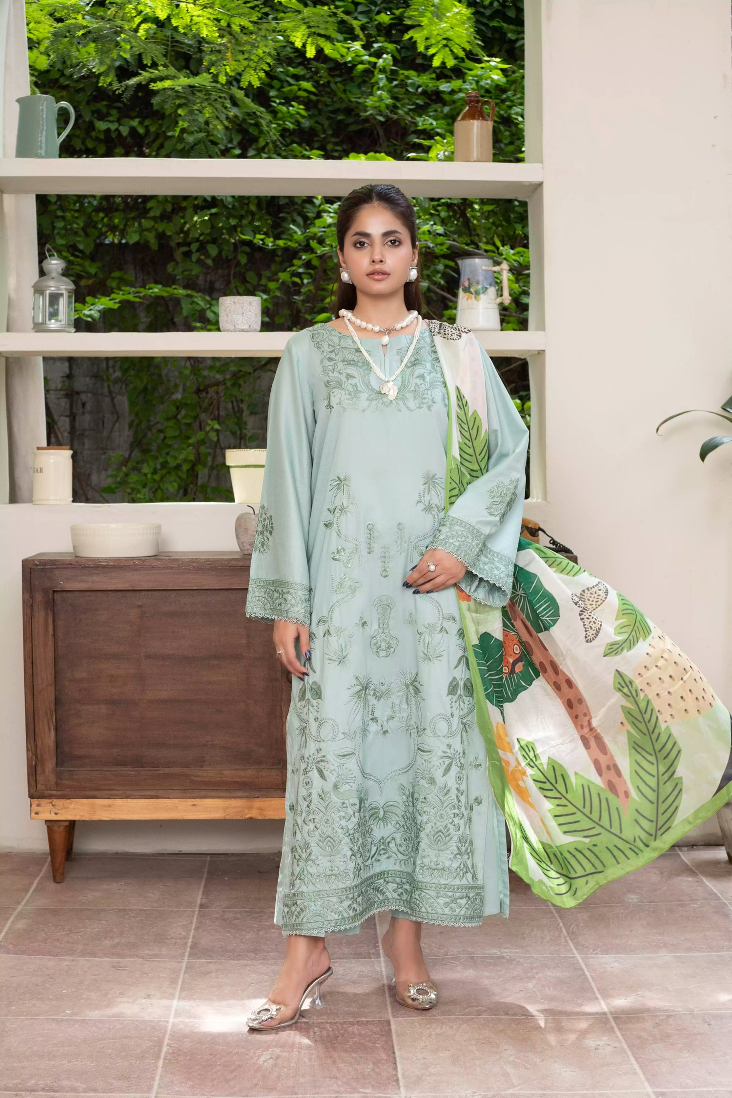 A pastel mint green design with embroidery on sleeves and intricate floral patterns, paired with a vibrant, tropical-themed printed dupatta. 